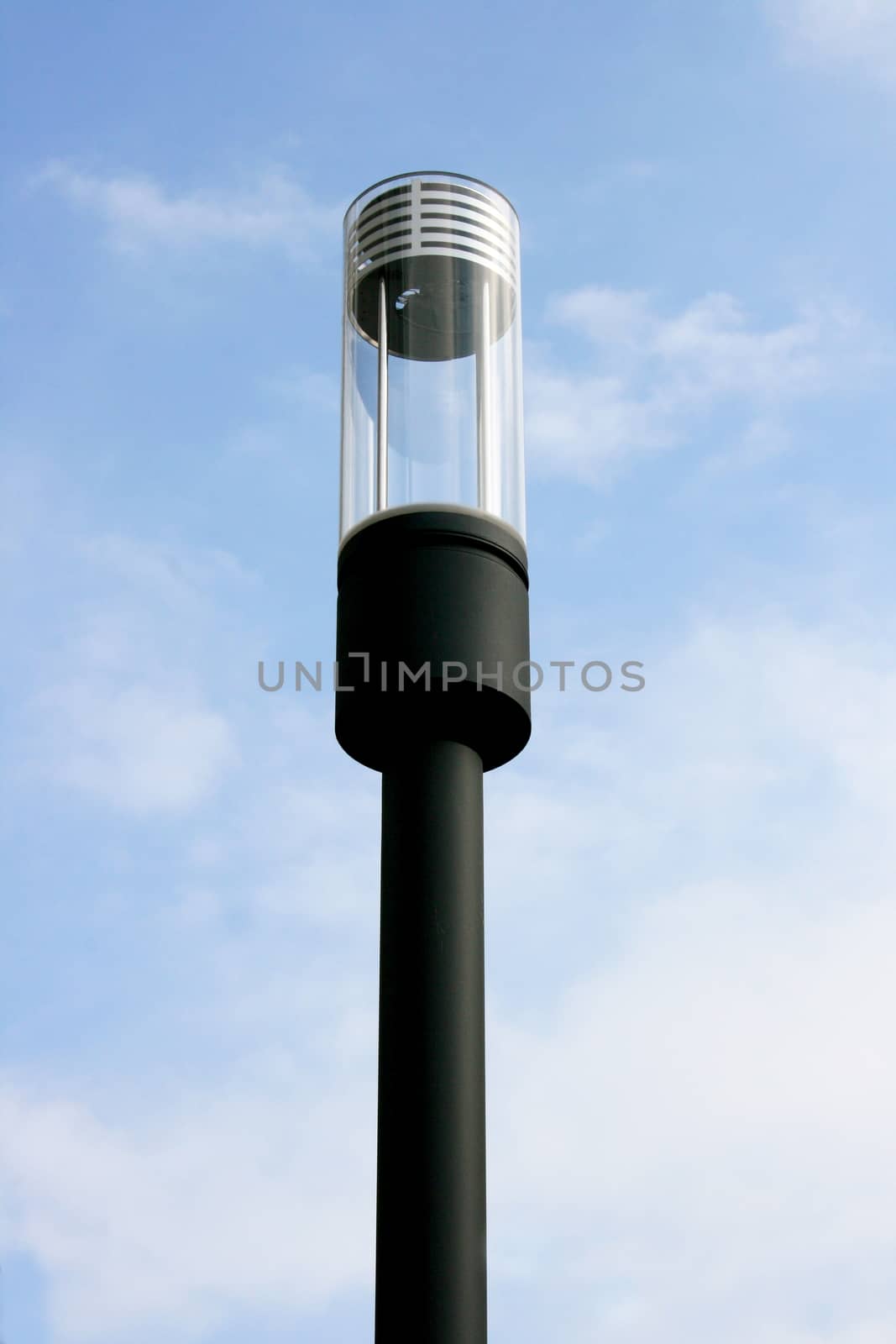 a modern, thin, zylindrige street lamp, blue sky in the background