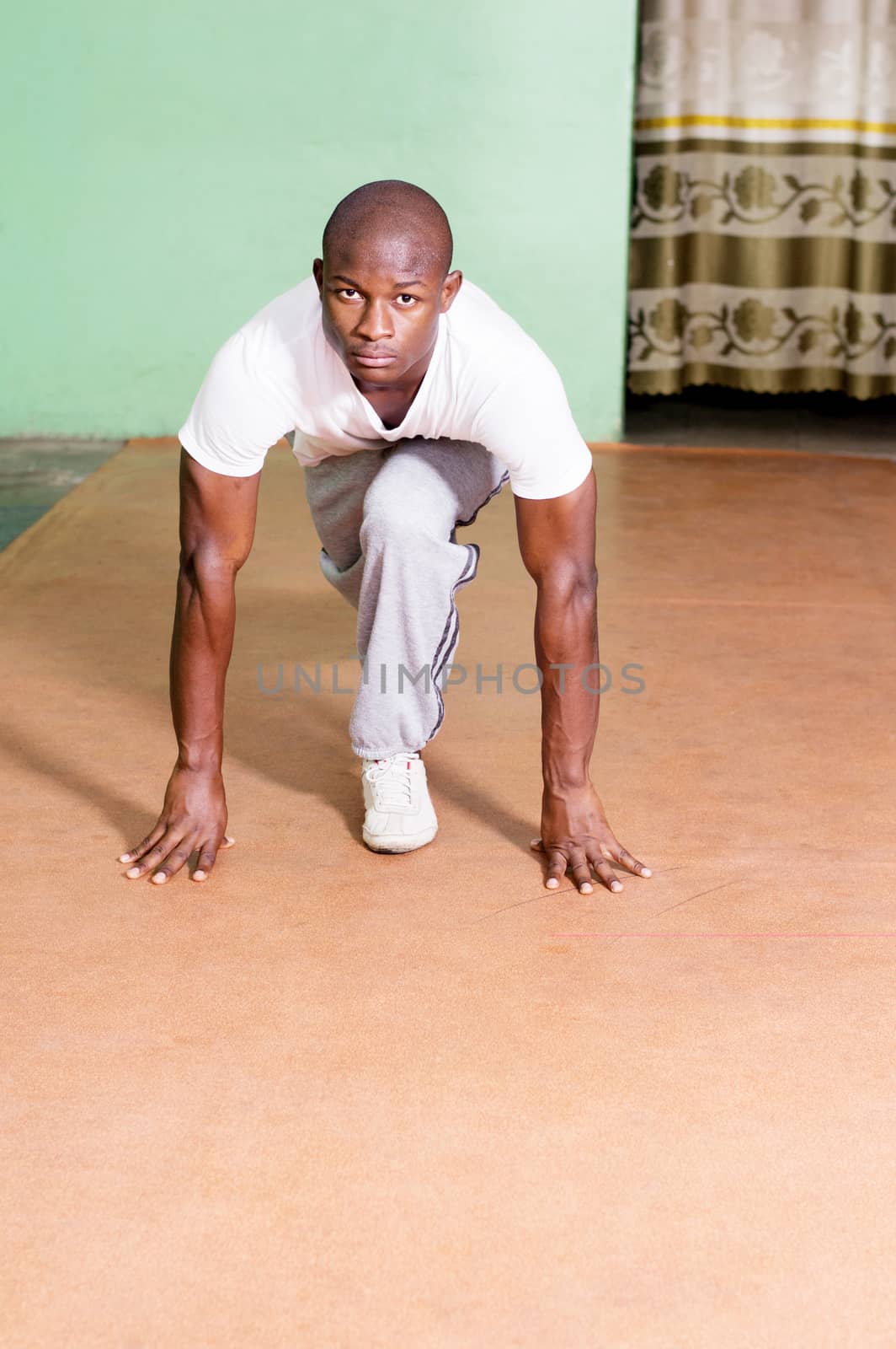 Young man in the starting position for a training race in the studio.