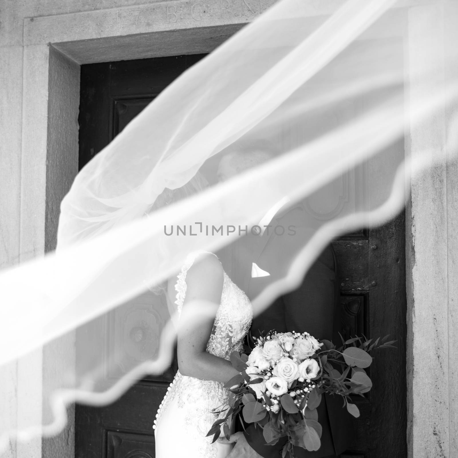 The kiss. Bride and groom kisses tenderly in the shadow of a flying veil. Artistic black and white wedding photo. by kasto