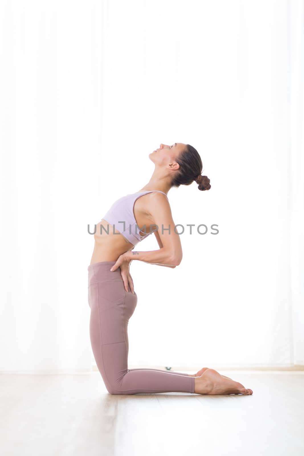 Portrait of gorgeous active sporty young woman practicing yoga in studio. Beautiful girl practice Ustrasana, camel yoga pose. Healthy active lifestyle, working out indoors in gym.