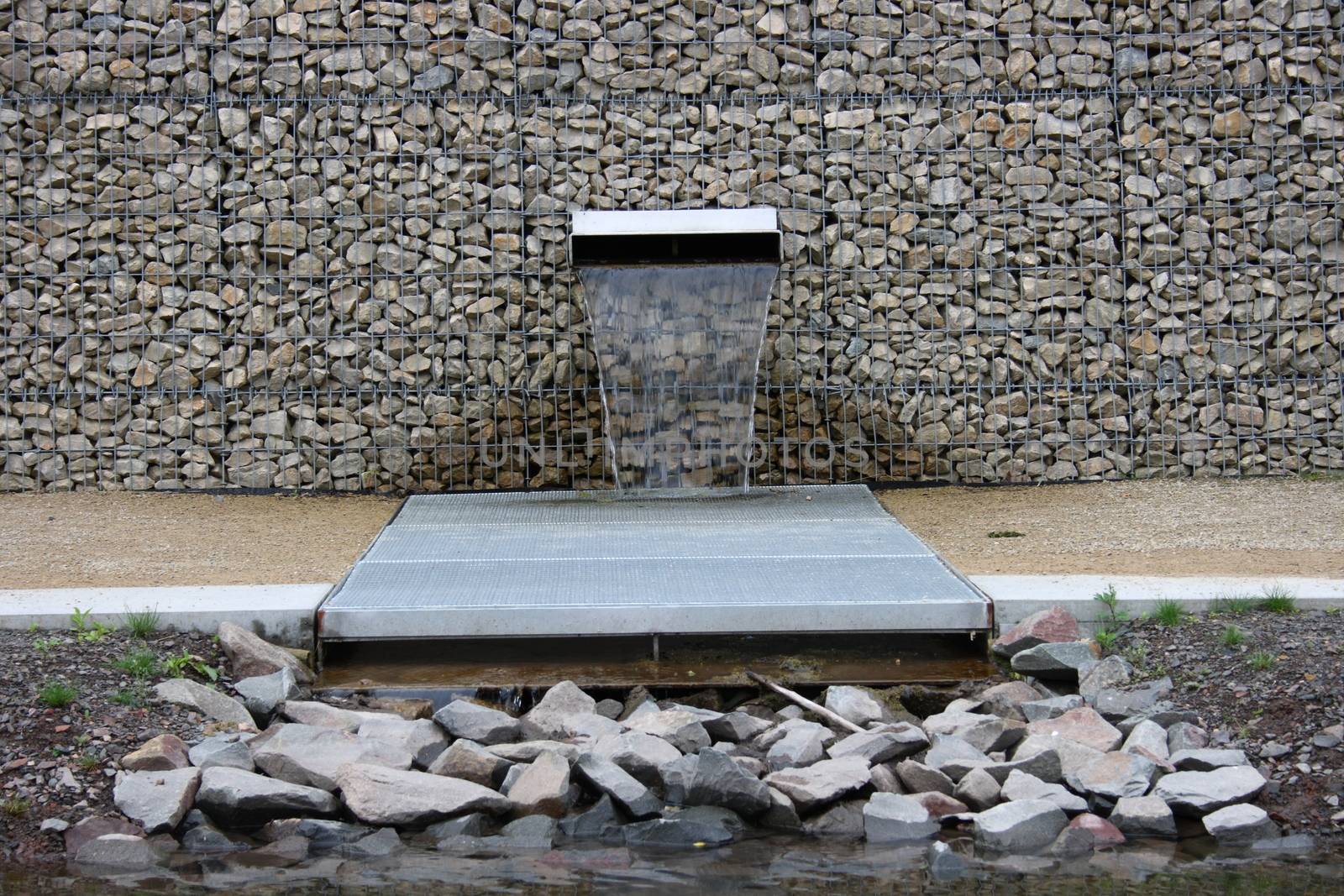 A stone wall built with gabions, from which water flows from