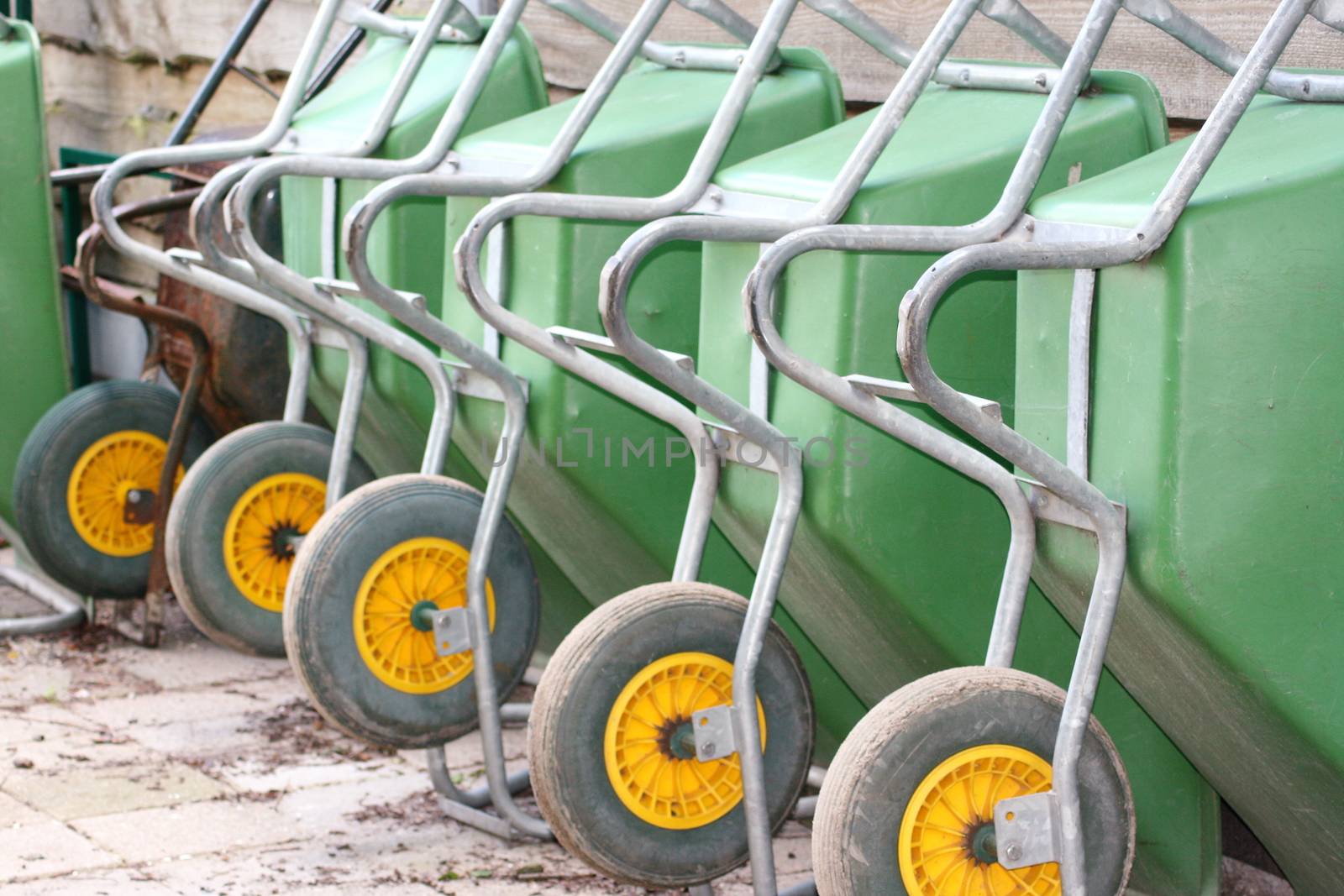 A erected in a row green wheelbarrow