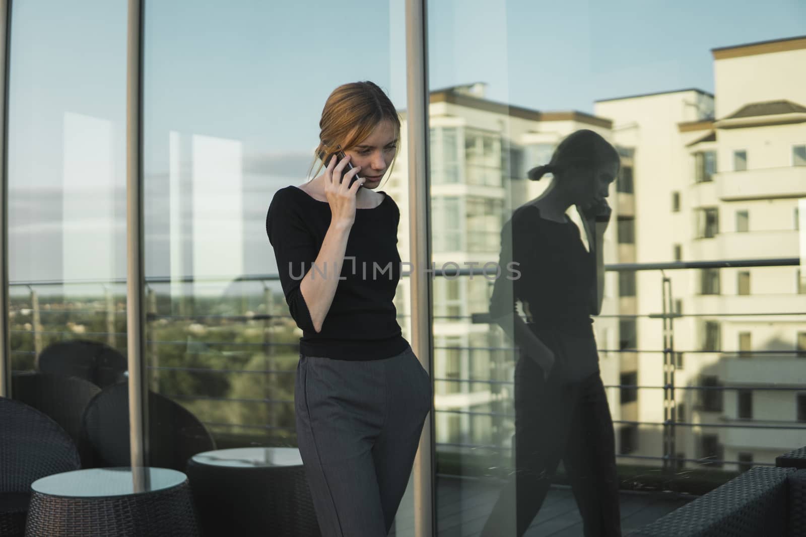 Young business woman using smart mobile phone, outside office building and speaking with a business partners. Business lady answering the phone with unhappy face, receiving bad news. Freelancer