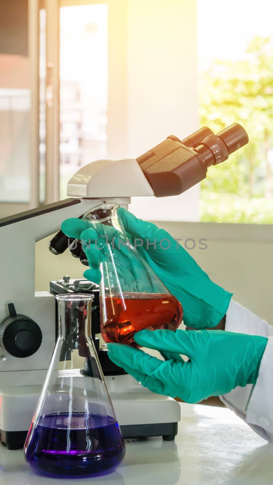 Laboratory beaker in analyst's hand in plastic glove