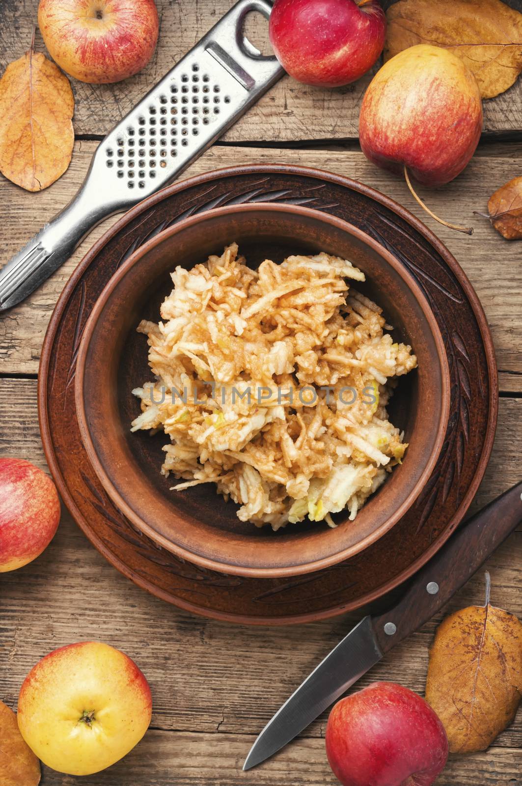 Grated ripe autumn apples in a plate on a wooden old table