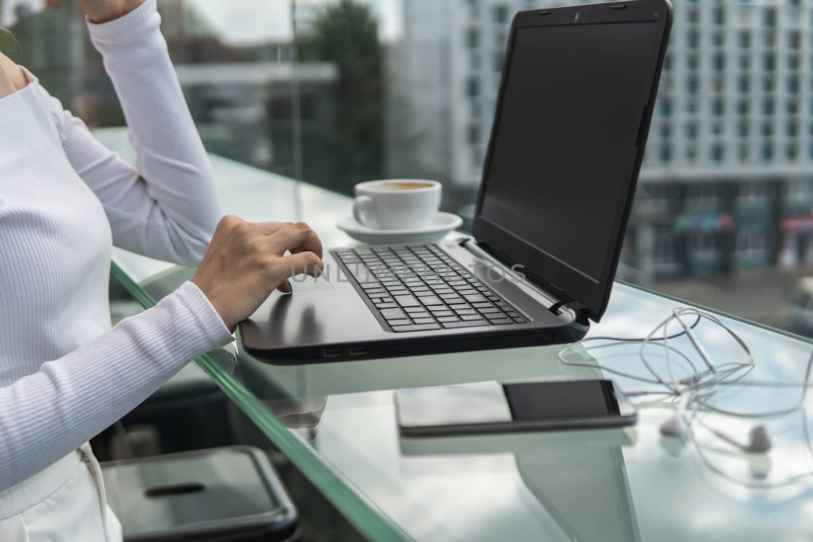 A woman is working by using a laptop computer on table. Hands typing on a keyboard. Female businessman is typing on a laptop keyboard sitting in cafe. by vovsht