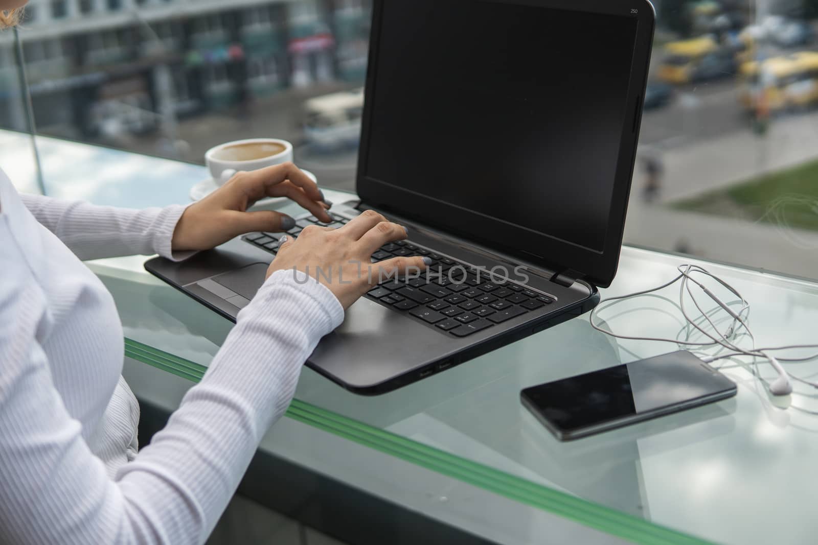 A woman is working by using a laptop computer on table. Hands typing on a keyboard. Female businessman is typing on a laptop keyboard sitting in cafe