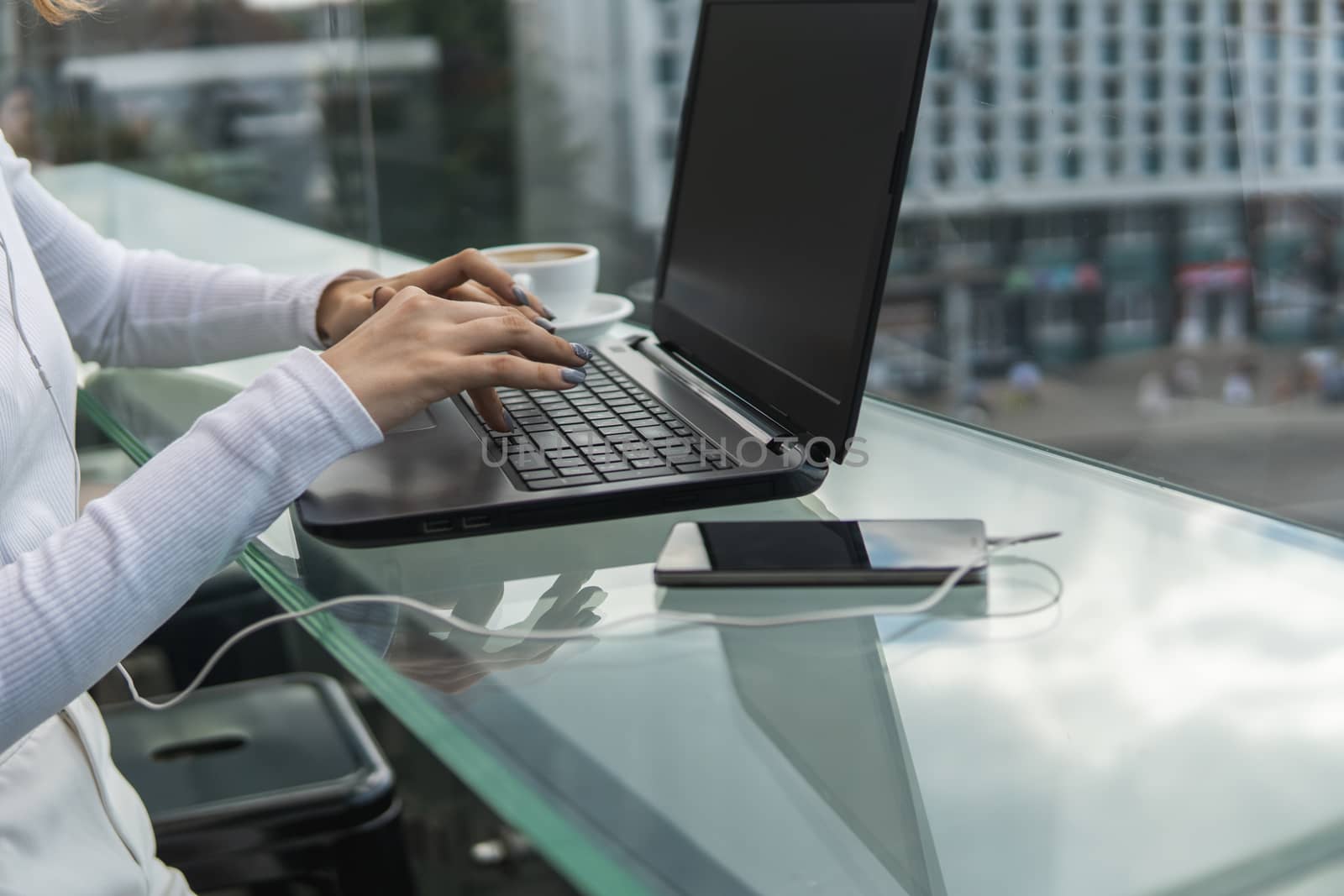 A woman is working by using a laptop computer on table. Hands typing on a keyboard. Female businessman is typing on a laptop keyboard sitting in cafe. by vovsht