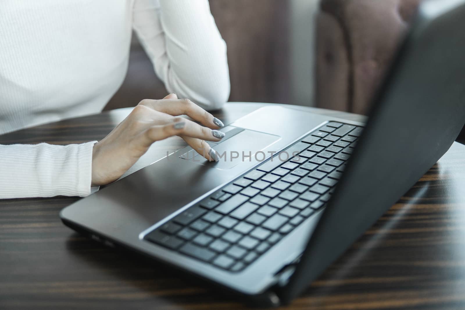 A woman is working by using a laptop computer on table. Hands typing on a keyboard. Female businessman is typing on a laptop keyboard sitting in cafe. by vovsht