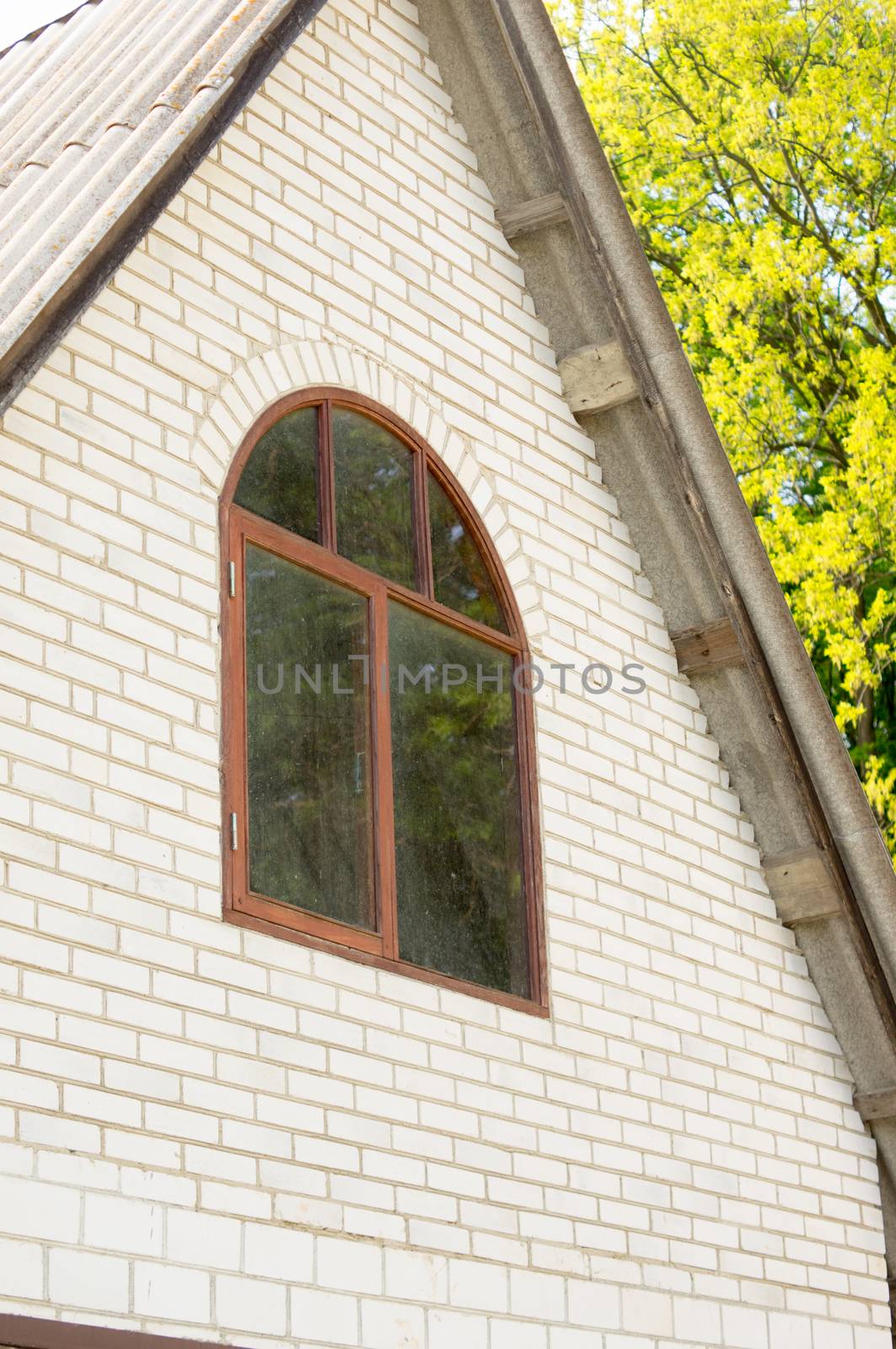facade of the house of brick brown attic with a window against the sky by Adamchuk