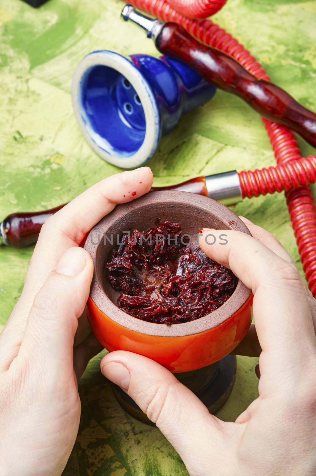 Refueling tobacco shisha with fruit tobacco.Detail of a hookah in hands.Oriental smoking hookah.