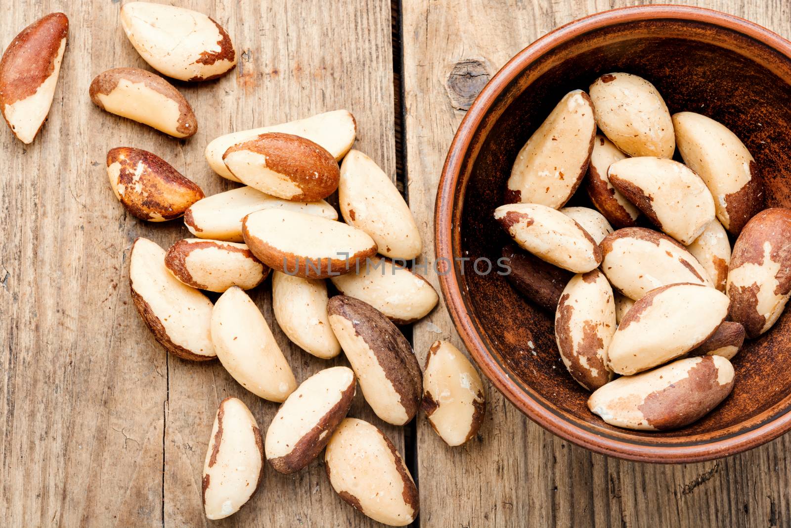 Tasty peeled brazil nut in bowl on old wooden table