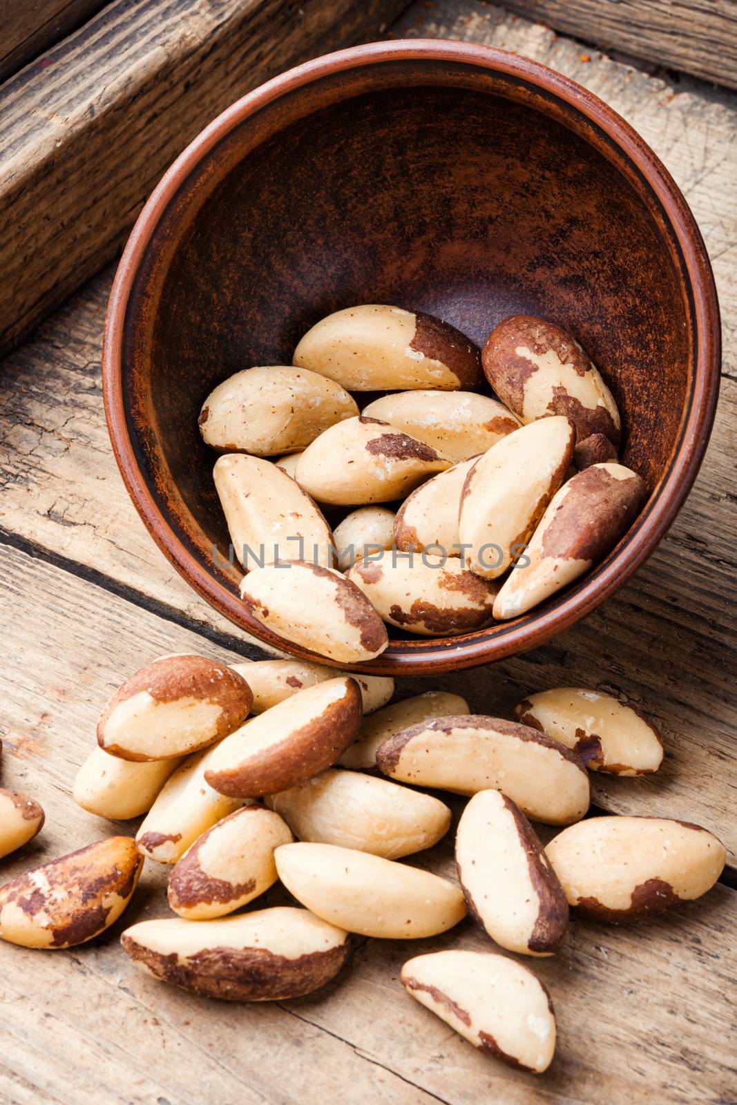 Tasty peeled brazil nut in bowl on old wooden table