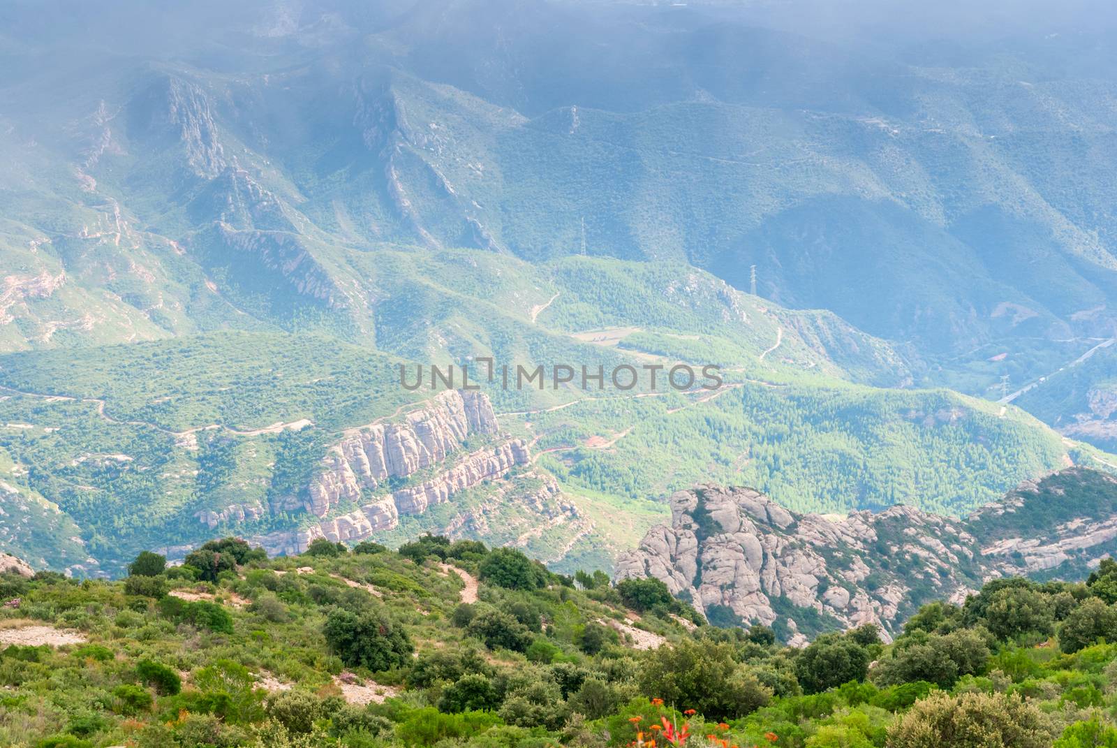 Hazy unusual mountains with green trees and cloudy sky near Montserrat Monastery,Spain by Zhukow