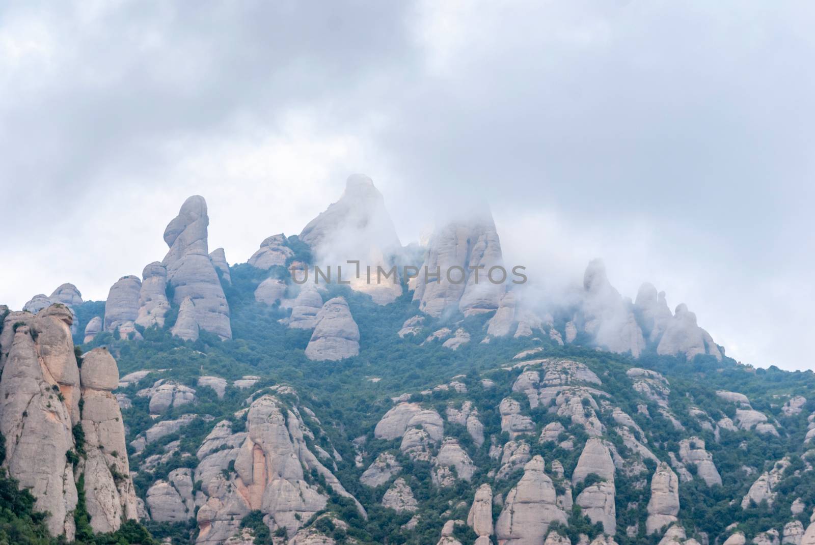 Hazy unusual mountains with green trees and cloudy sky near Montserrat Monastery,Spain. Catalonia
