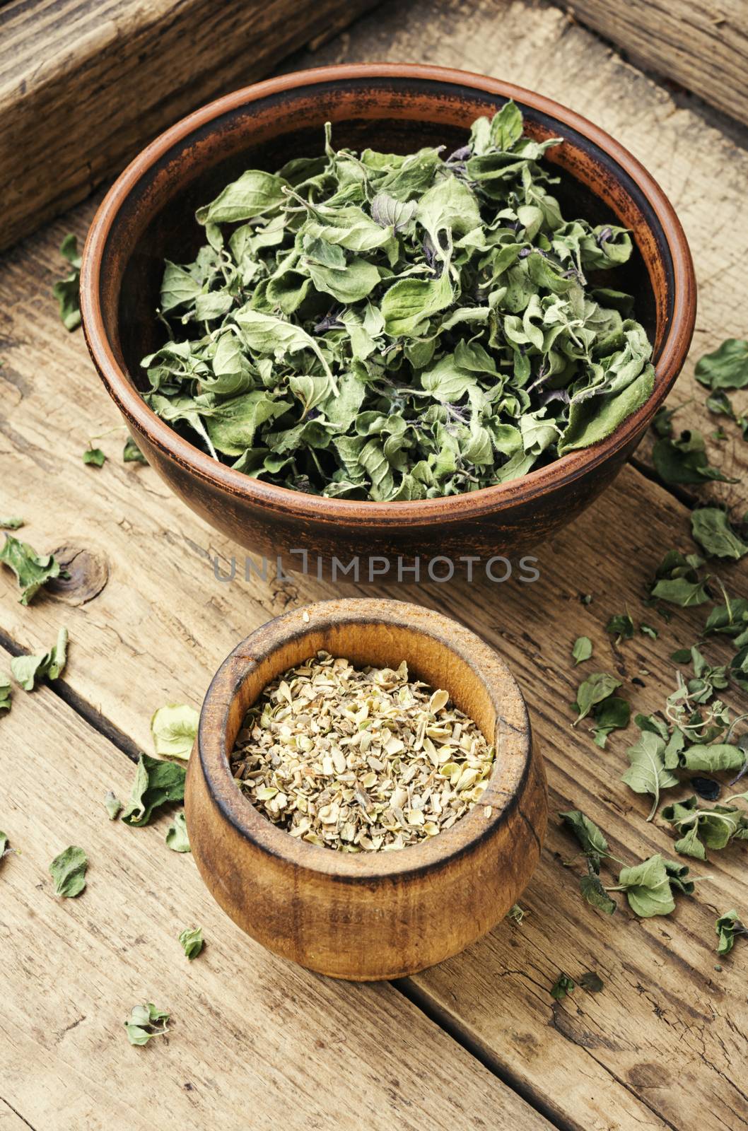 Bowl with dried oregano on old wooden table