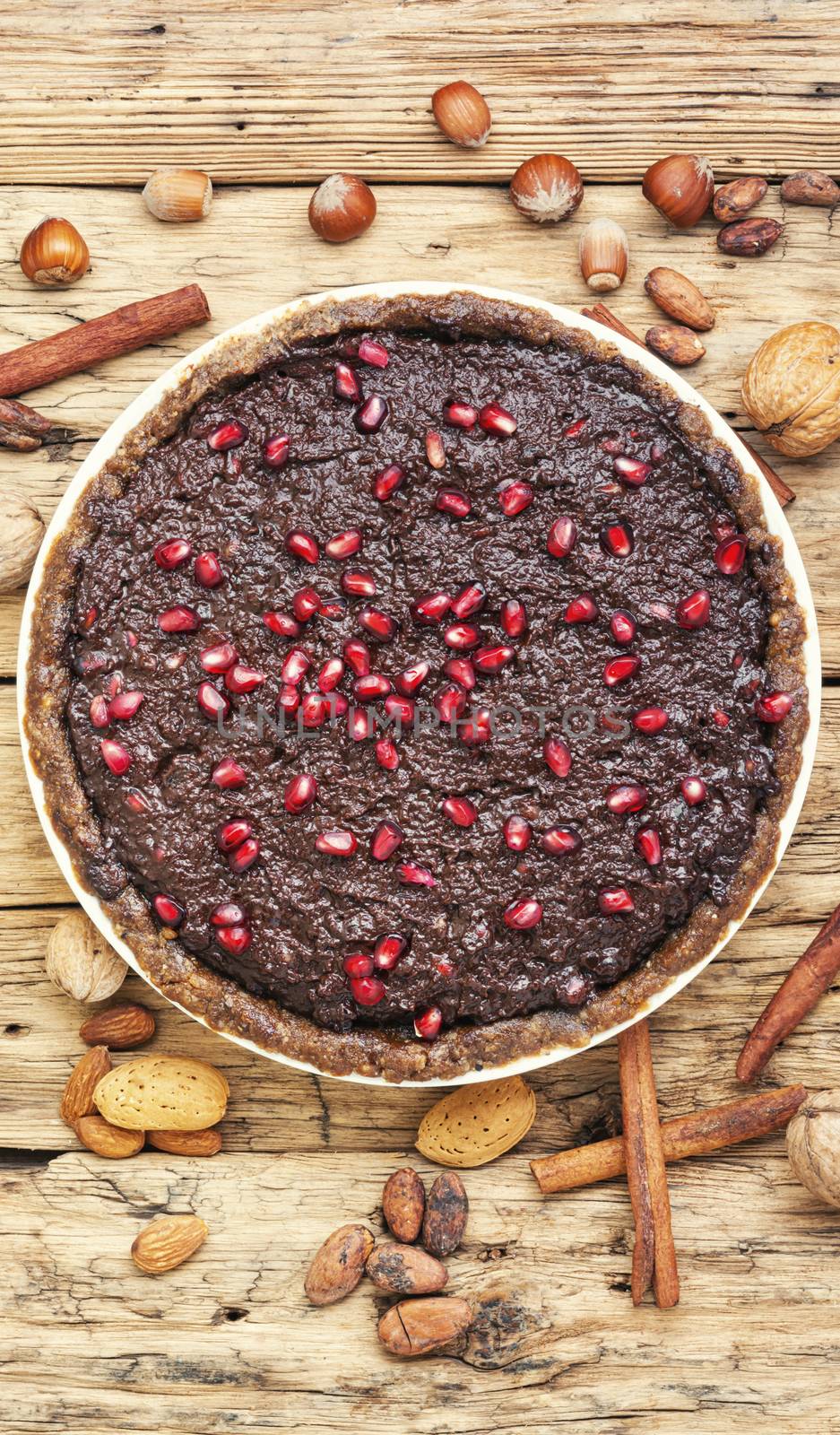 Tasty chocolate cake with pomegranate on a wooden background.