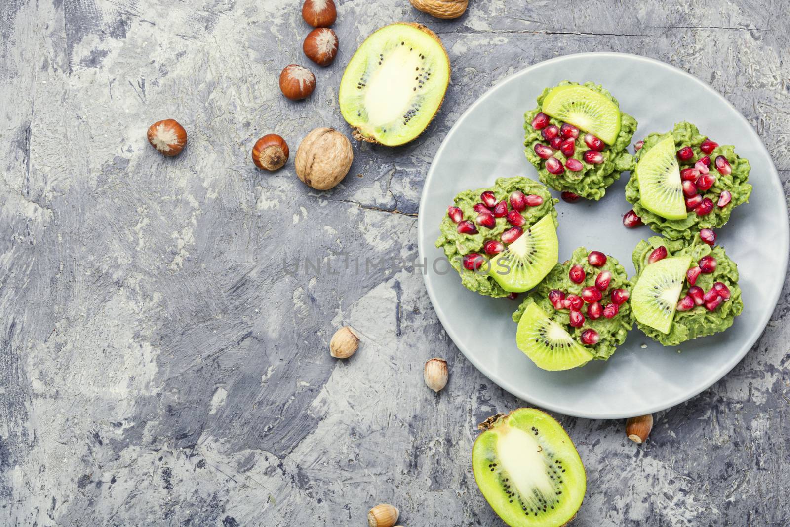 Diet avocado cupcakes or muffin garnished with kiwi and pomegranate.Fairy cake.Space for text