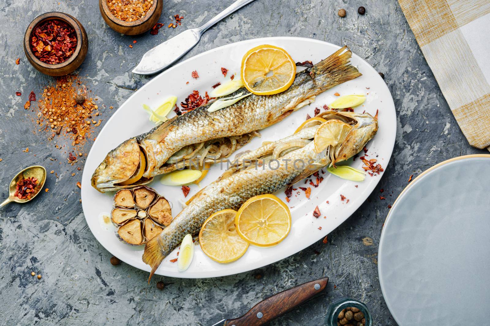 Pelengas baked with vegetables and pomegranate.Cooked roasted fish in a baking dish.