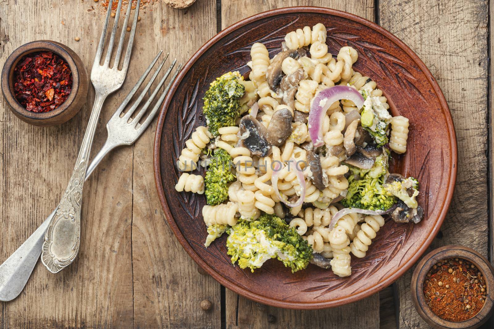 Broccoli and pasta with mushrooms.Vegetarian vegetable pasta wooden table.