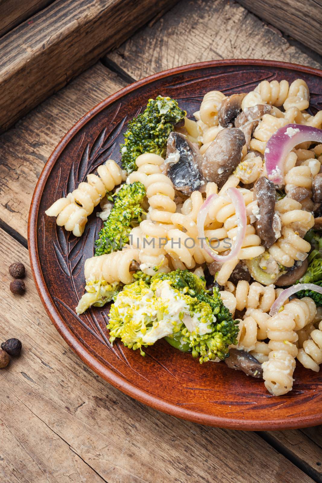 Baked broccoli and pasta with mushrooms.Vegetarian vegetable pasta wooden table.