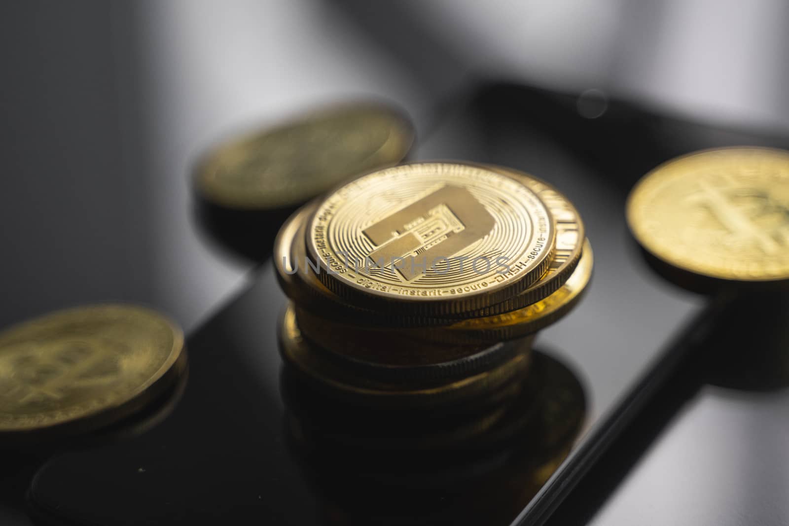 Stack of golden Dash bitcoin coin on a smartphone with a lot of bitcoins coins on a table. Virtual cryptocurrency concept. Mining of bitcoins online bussiness. Bitcoins trading