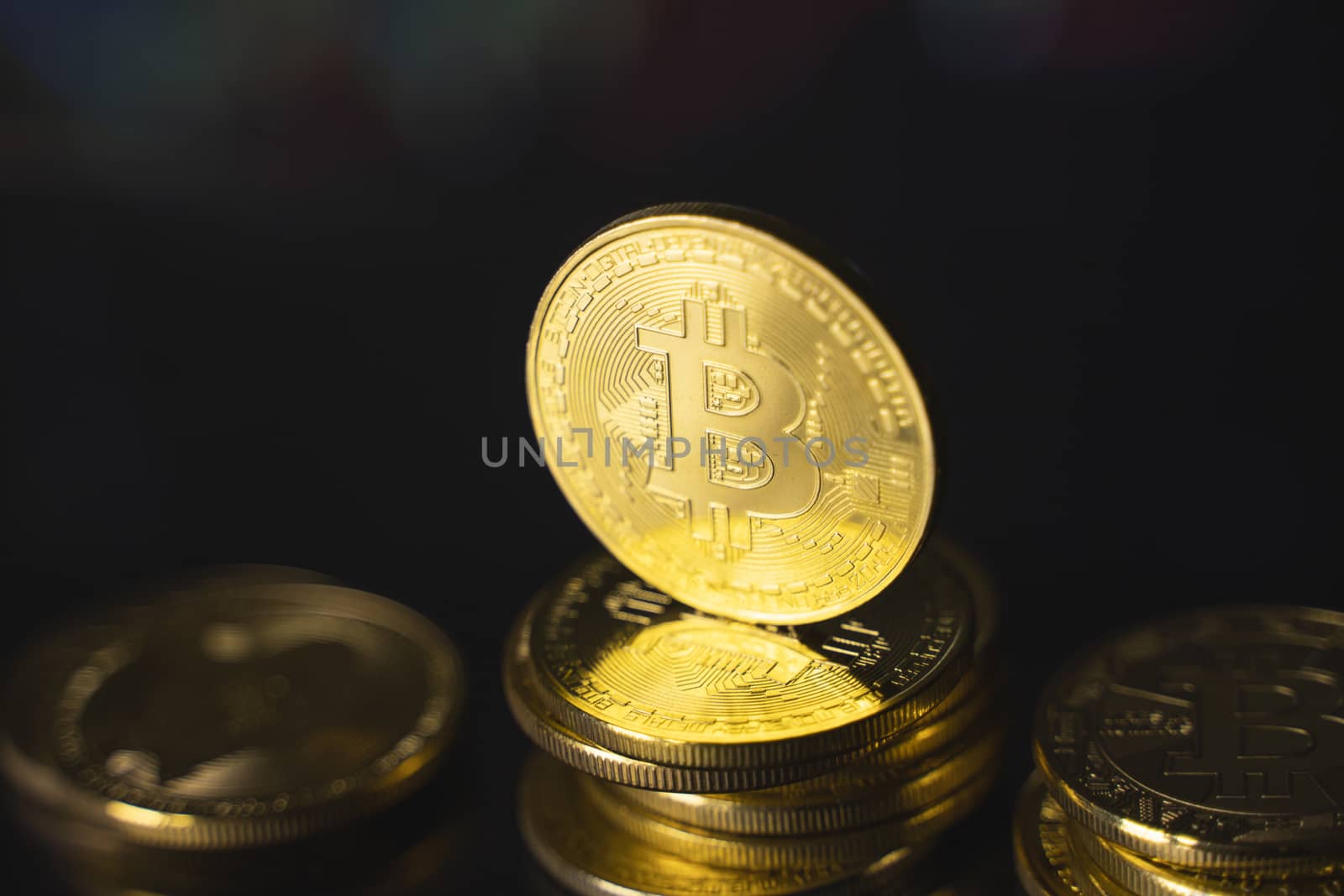 Bitcoins and virtual money concept. Gold bitcoins on a stack of coins with chart of growing and falling valuance of a cryptocurrency. Mining or blockchain technology. by vovsht