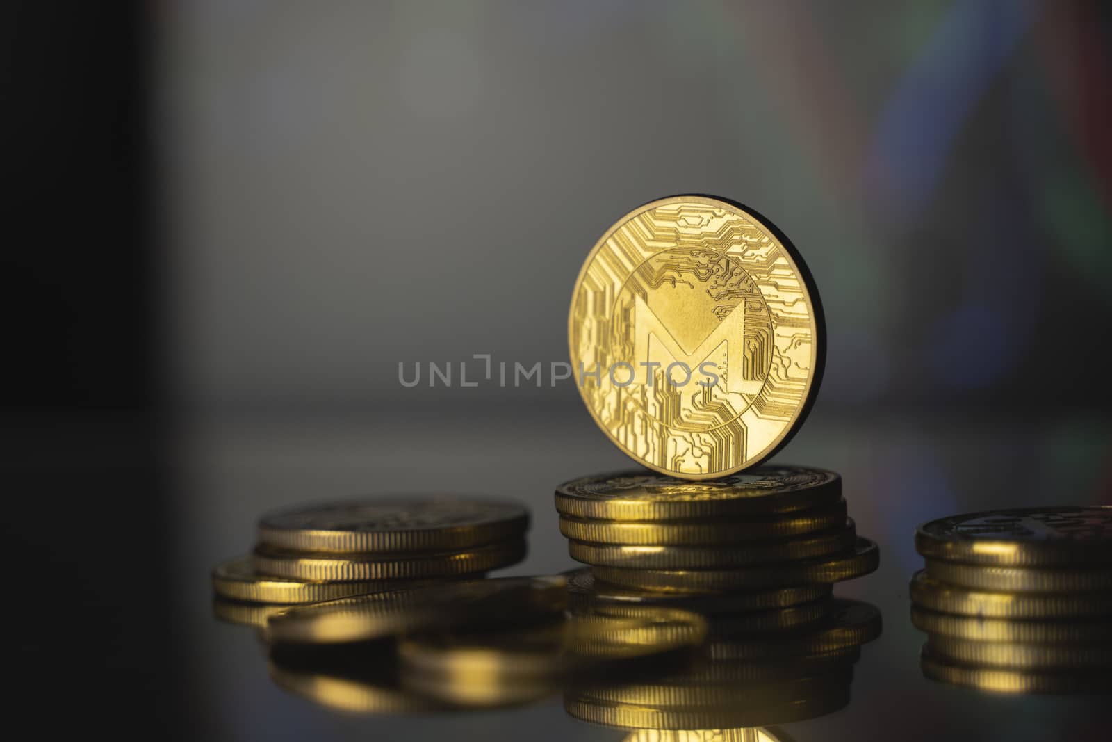 Monero and virtual money concept. Gold monero bitcoins on a stack of coins with chart of growing and falling valuance of a cryptocurrency. Mining or blockchain technology