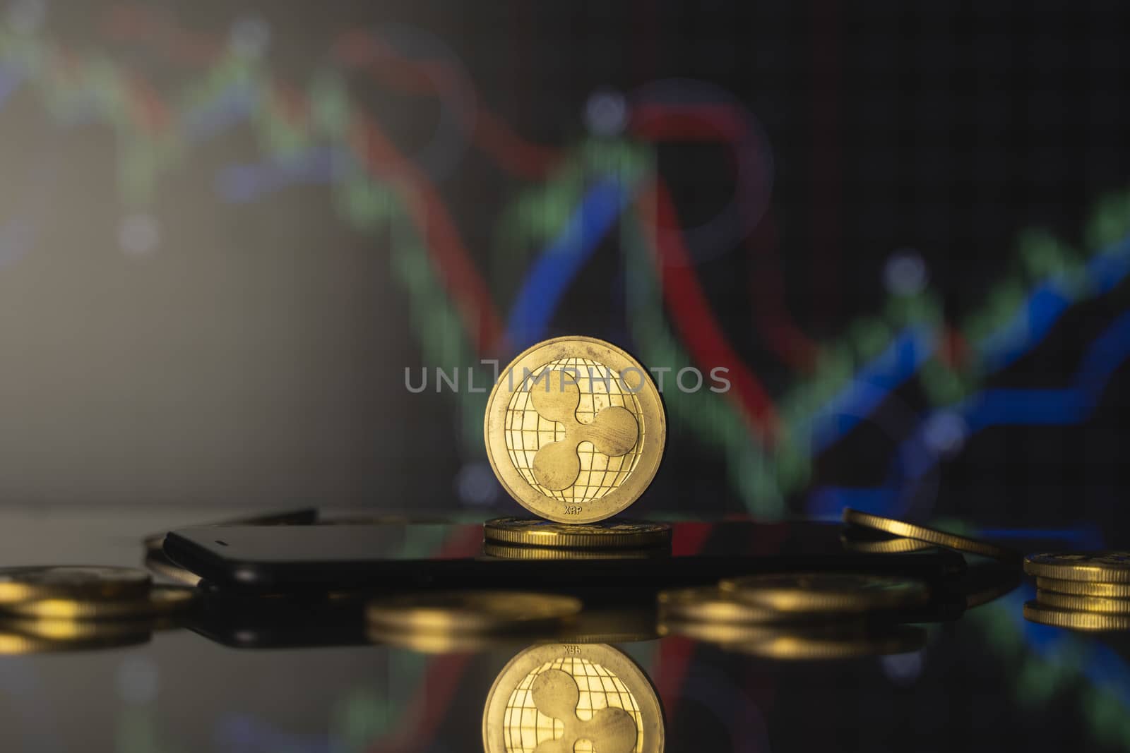 Ripple coin and virtual money concept. Gold Ripple on a stack of coins with chart of growing and falling valuance of a cryptocurrency. Mining or blockchain technology