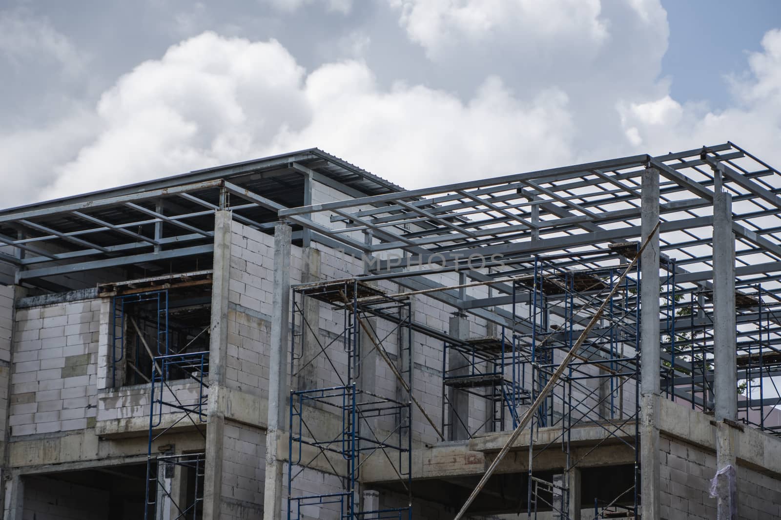 Building and Construction Site in progress. Building construction site against cloudy sky. Metal construction of unfinished building on construction of multi storage building. by vovsht