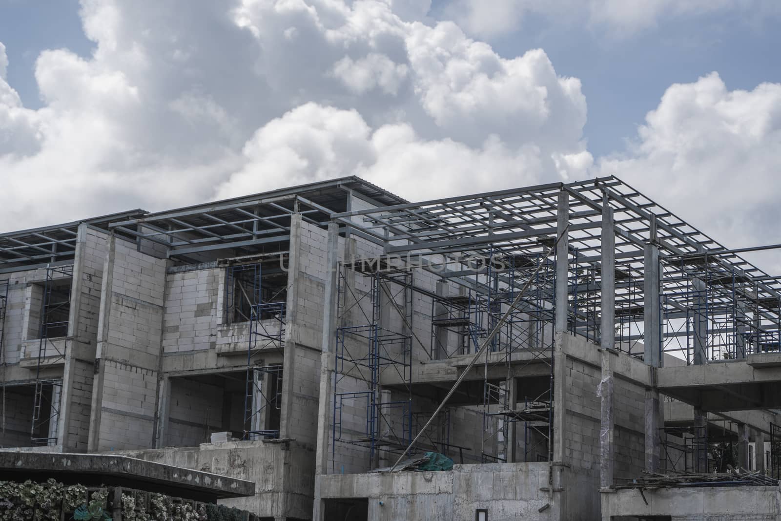 Building and Construction Site in progress. Building construction site against cloudy sky. Metal construction of unfinished building on construction of multi storage building. by vovsht