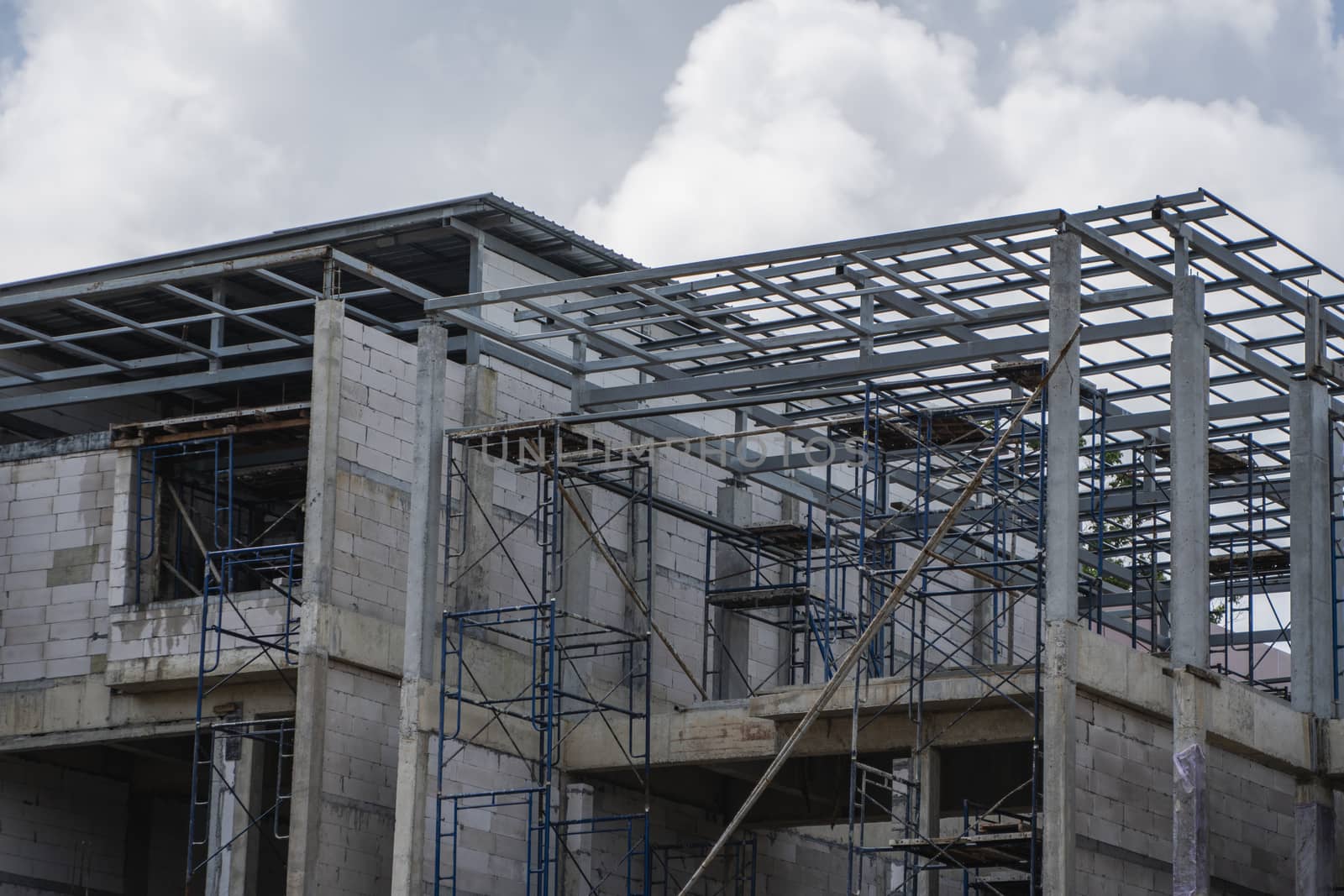 Building and Construction Site in progress. Building construction site against cloudy sky. Metal construction of unfinished building on construction of multi storage building. by vovsht