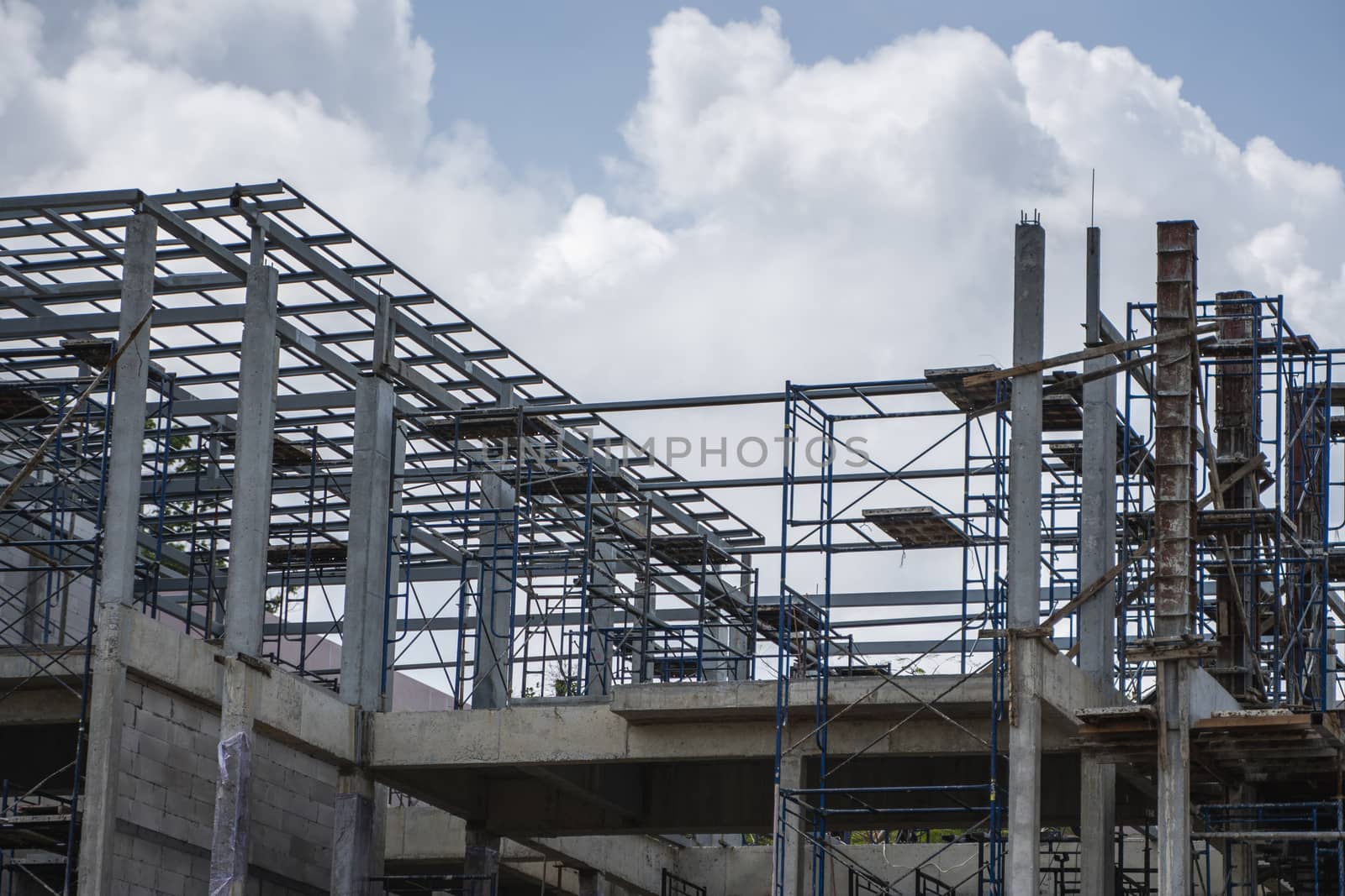 Building and Construction Site in progress. Building construction site against cloudy sky. Metal construction of unfinished building on construction of multi storage building. by vovsht