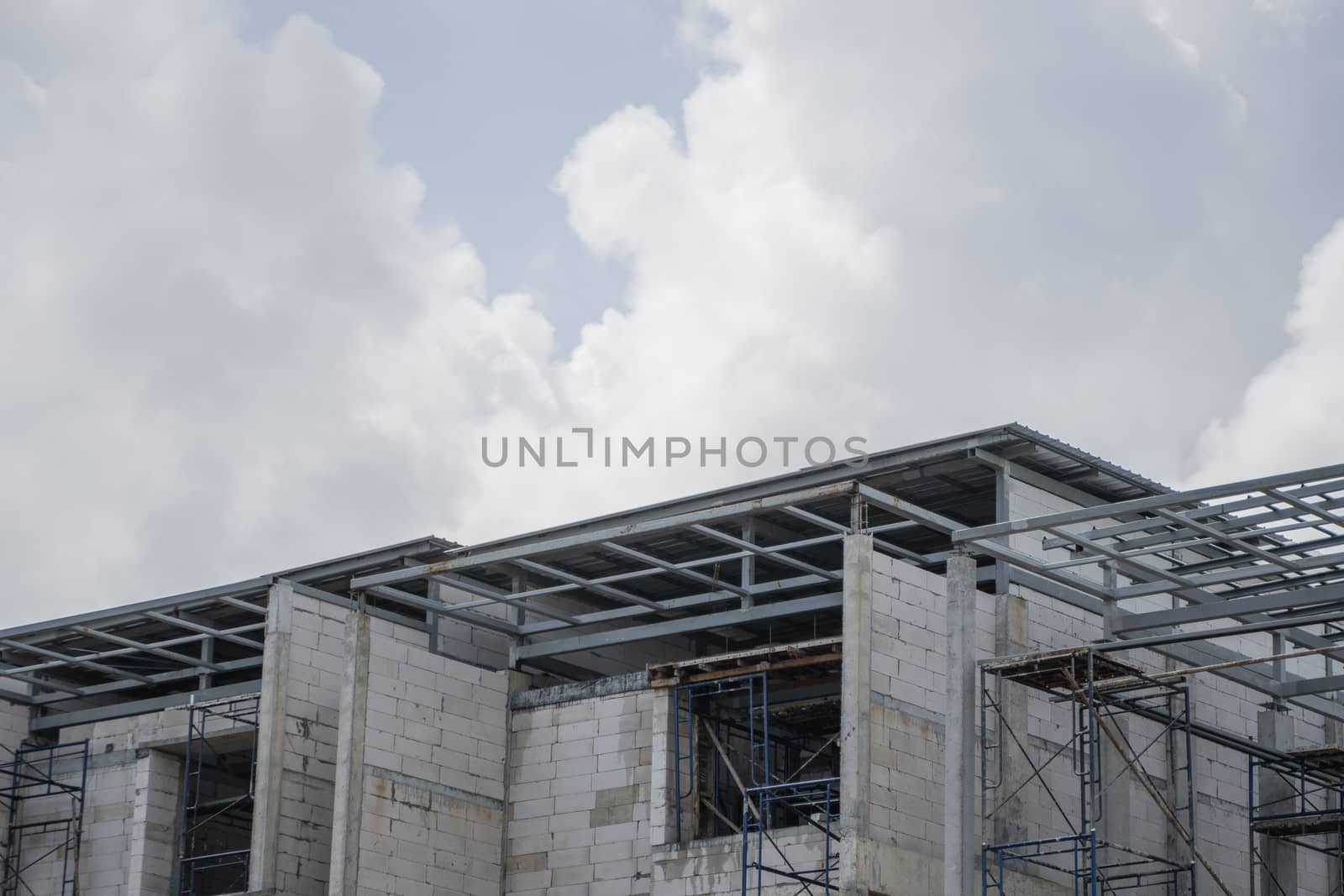 Building and Construction Site in progress. Building construction site against cloudy sky. Metal construction of unfinished building on construction of multi storage building