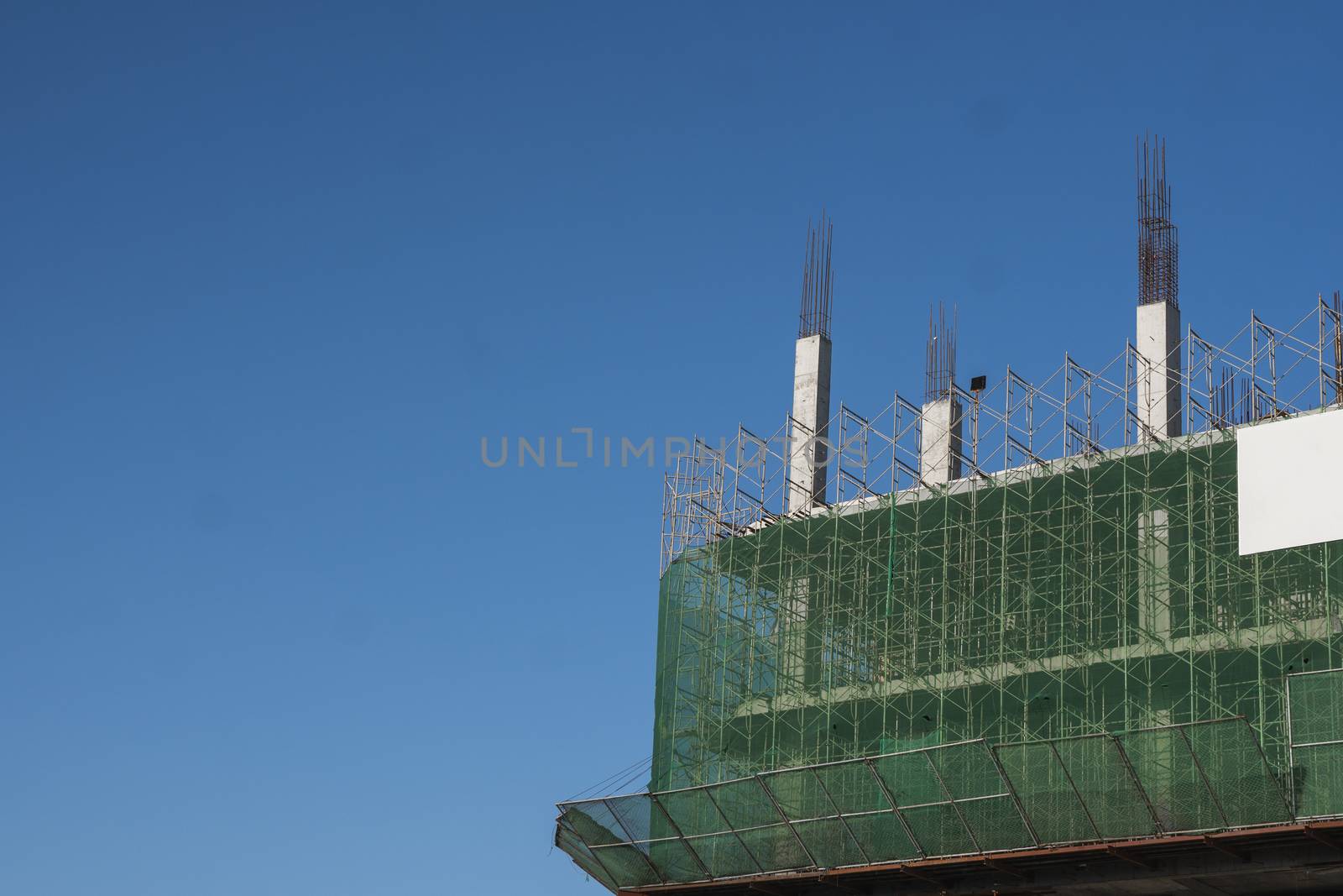 Building and Construction Site in progress. Building construction site against blue sky. Metal construction of unfinished building on construction of multi storage building. by vovsht