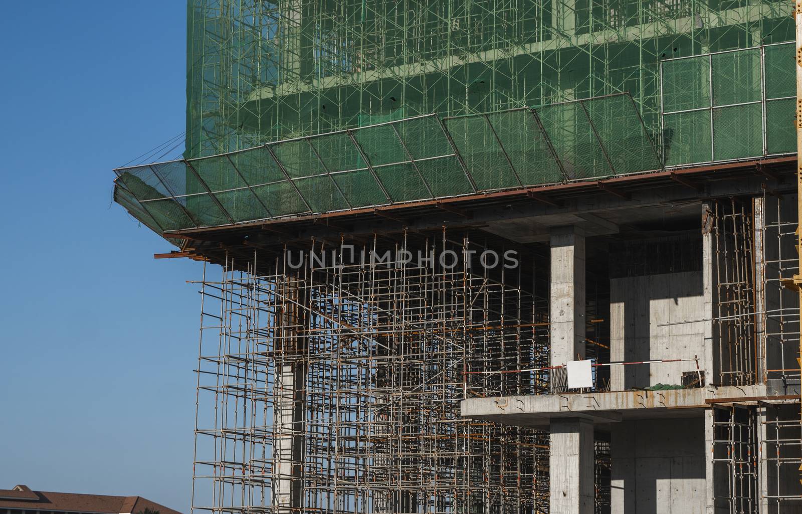 Building and Construction Site in progress. Building construction site against blue sky. Metal construction of unfinished building on construction of multi storage building