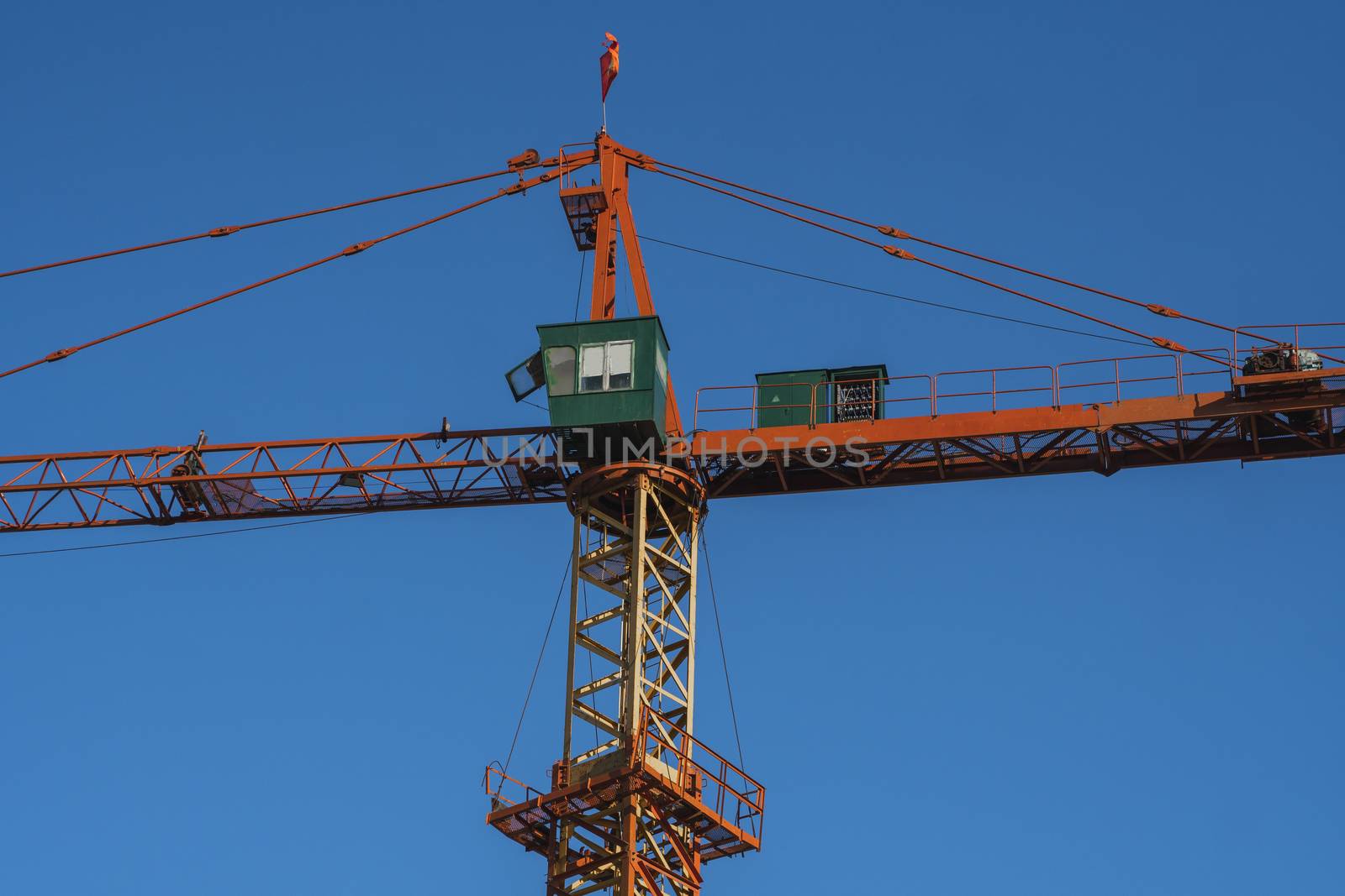 Tower crane against blue sky on a construction site for building of multi storage building or another type of structure. by vovsht