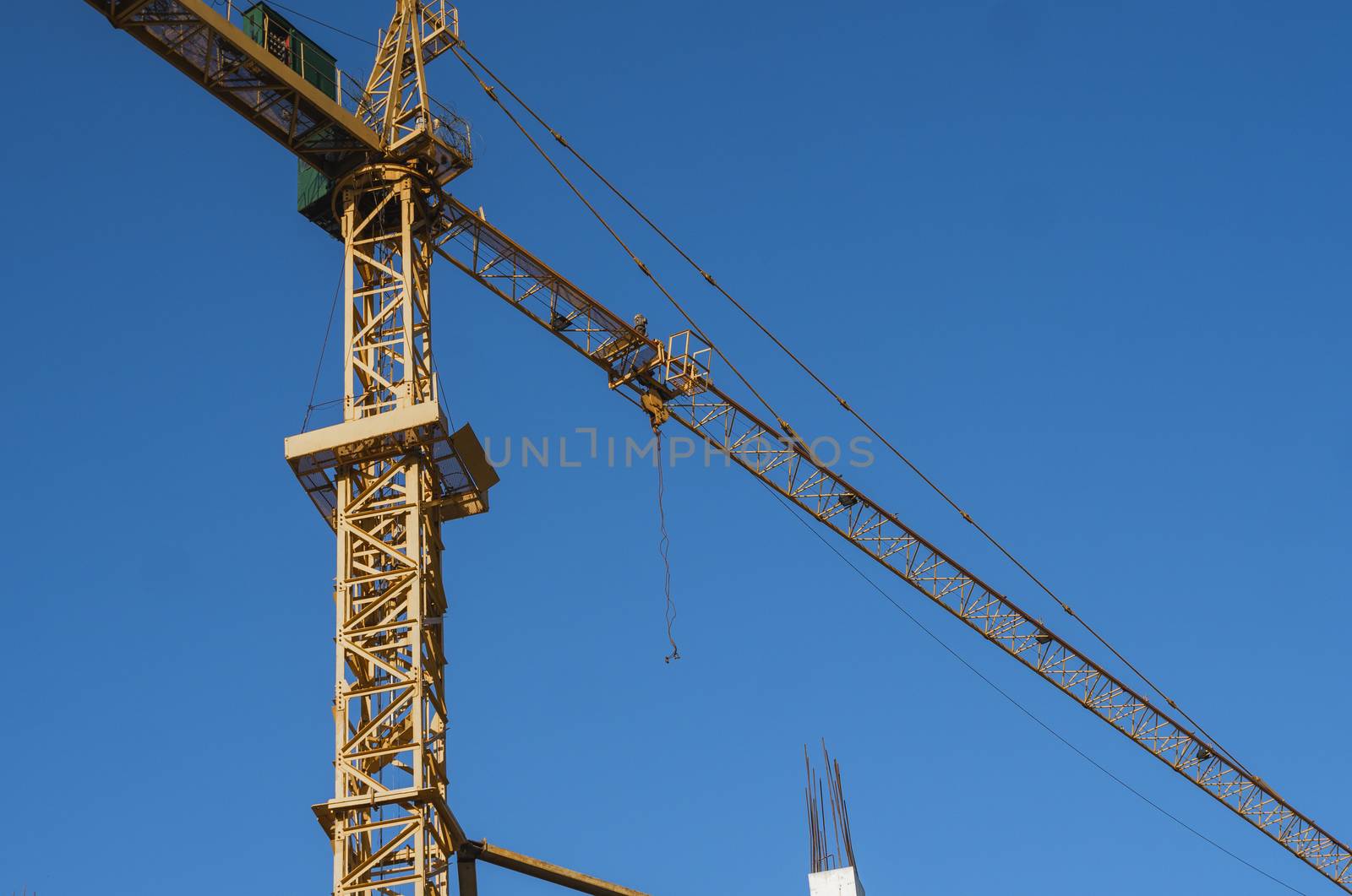 Tower crane against blue sky on a construction site for building of multi storage building or another type of structure. by vovsht