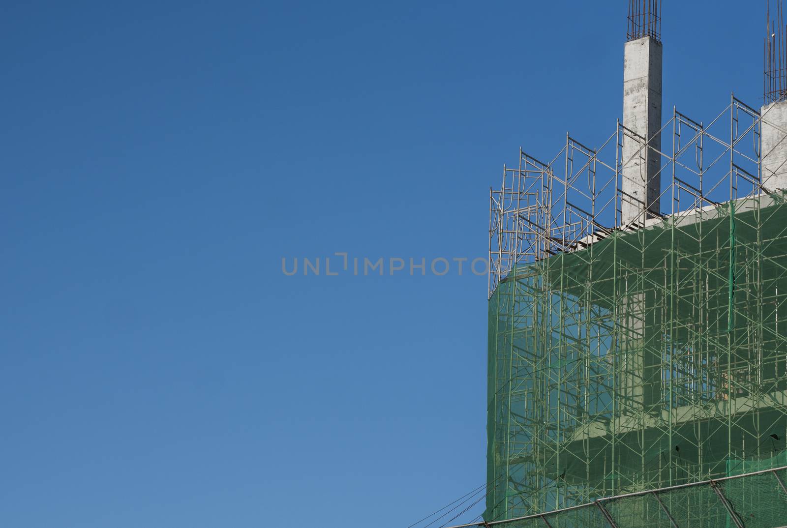 Building and Construction Site in progress. Building construction site against blue sky. Metal construction of unfinished building on construction of multi storage building