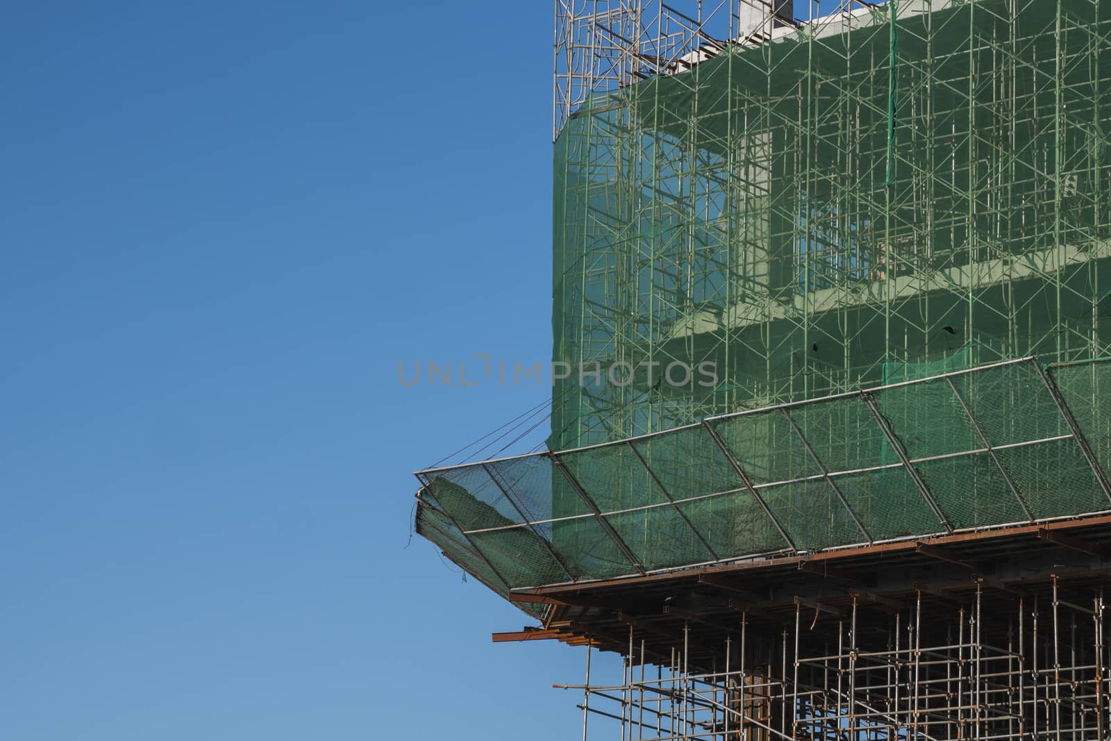 Building and Construction Site in progress. Building construction site against blue sky. Metal construction of unfinished building on construction of multi storage building
