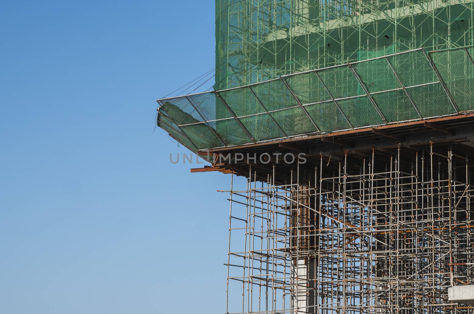 Building and Construction Site in progress. Building construction site against blue sky. Metal construction of unfinished building on construction of multi storage building. by vovsht