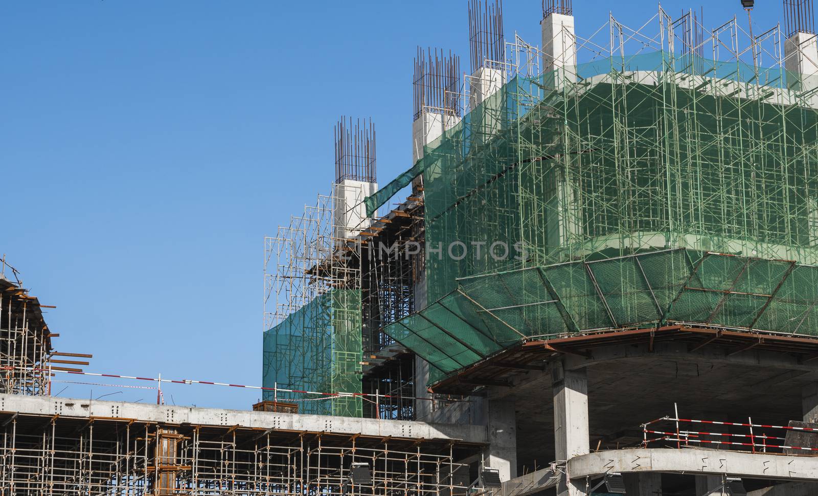 Building and Construction Site in progress. Building construction site against blue sky. Metal construction of unfinished building on construction of multi storage building. by vovsht