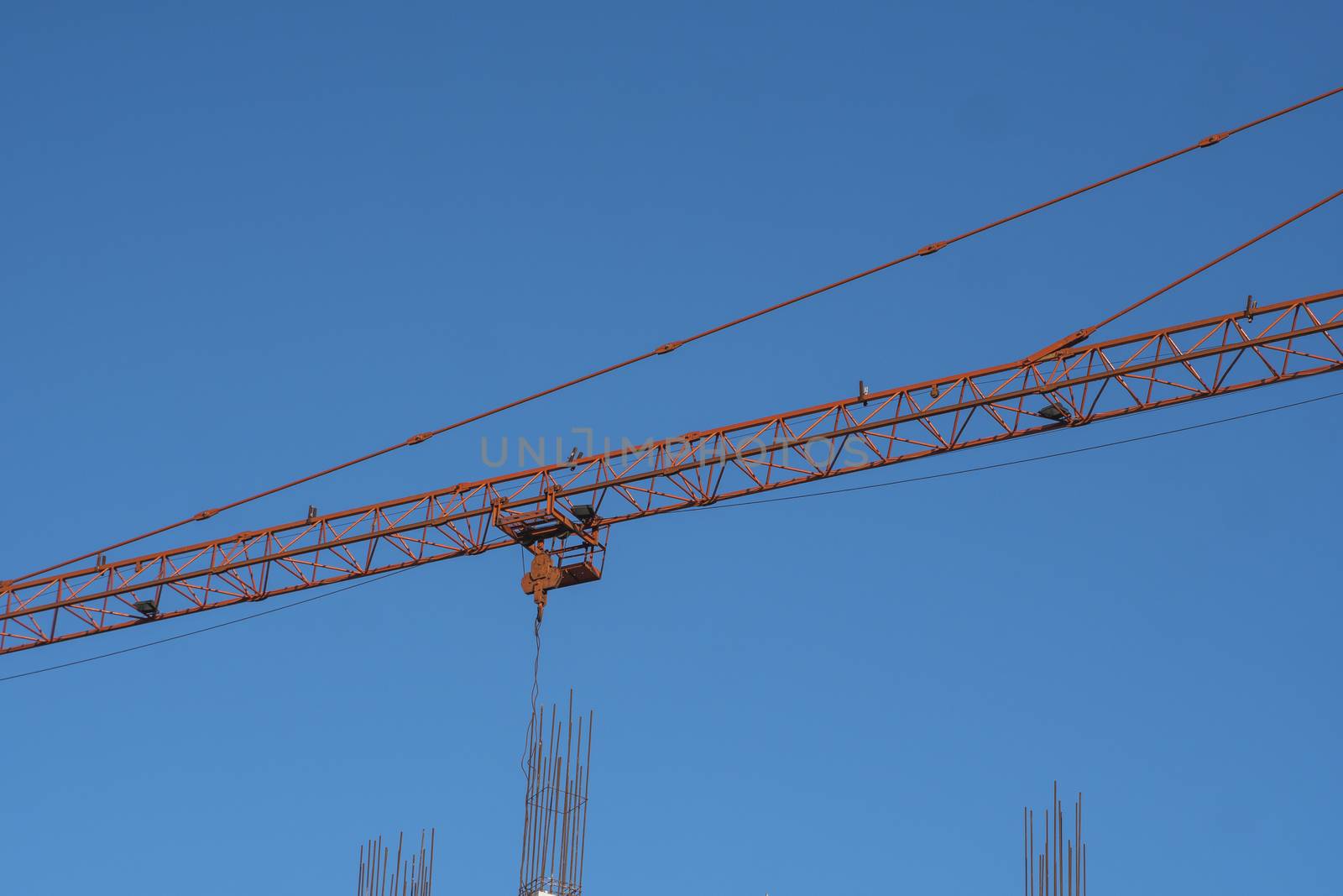 Tower crane against blue sky on a construction site for building of multi storage building or another type of structure