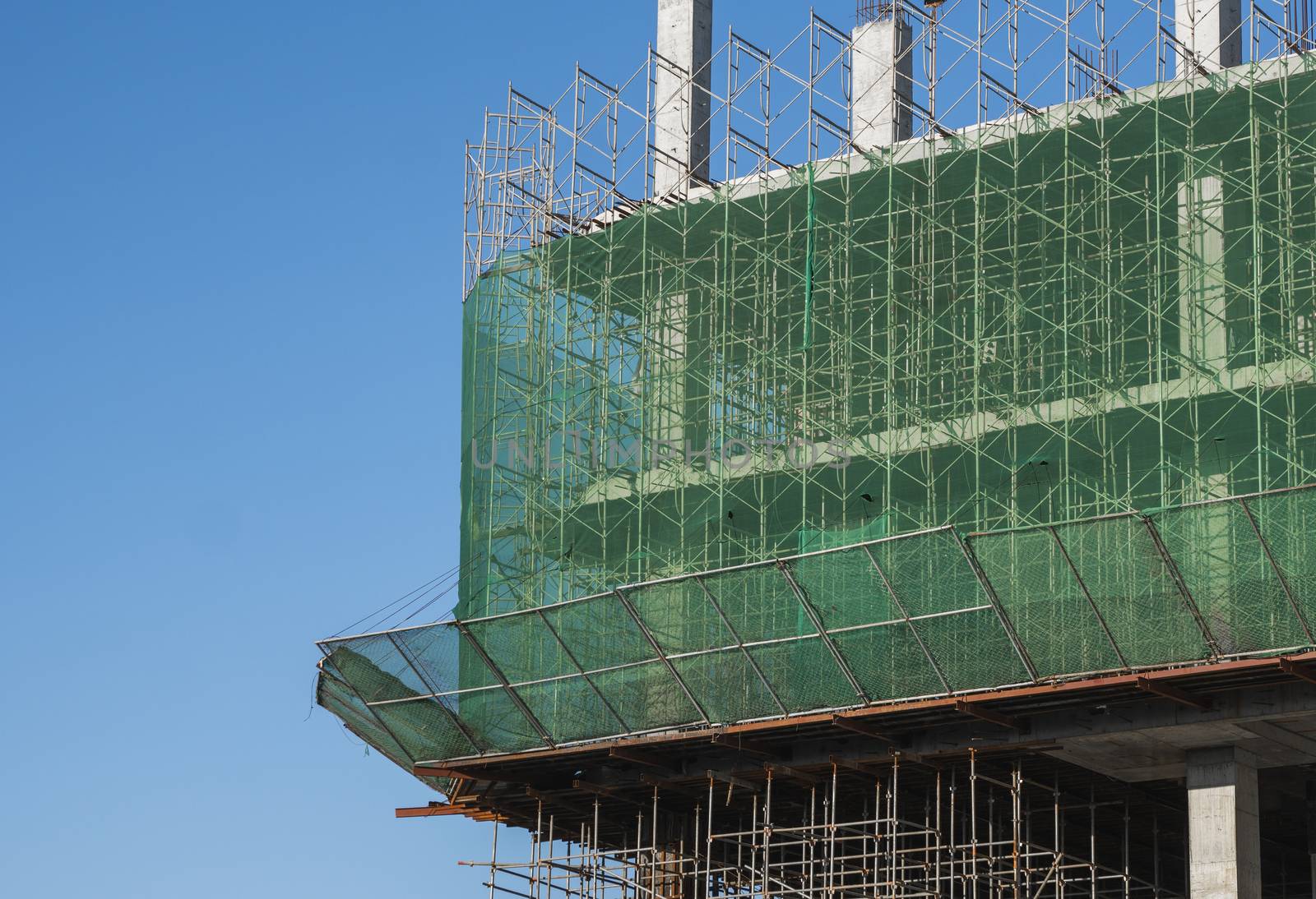 Building and Construction Site in progress. Building construction site against blue sky. Metal construction of unfinished building on construction of multi storage building. by vovsht