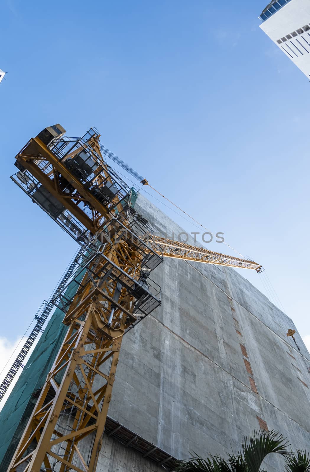 Crane and building construction site against blue sky. Metal construction of unfinished building on construction. Tower Crane use for building of multi storage building