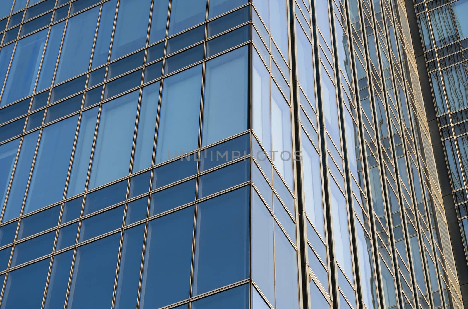 Reflection of the sky in the windows of a building. Perspective and underdite angle view to modern glass building skyscrapers over blue sky. Windows of Bussiness office or corporate building