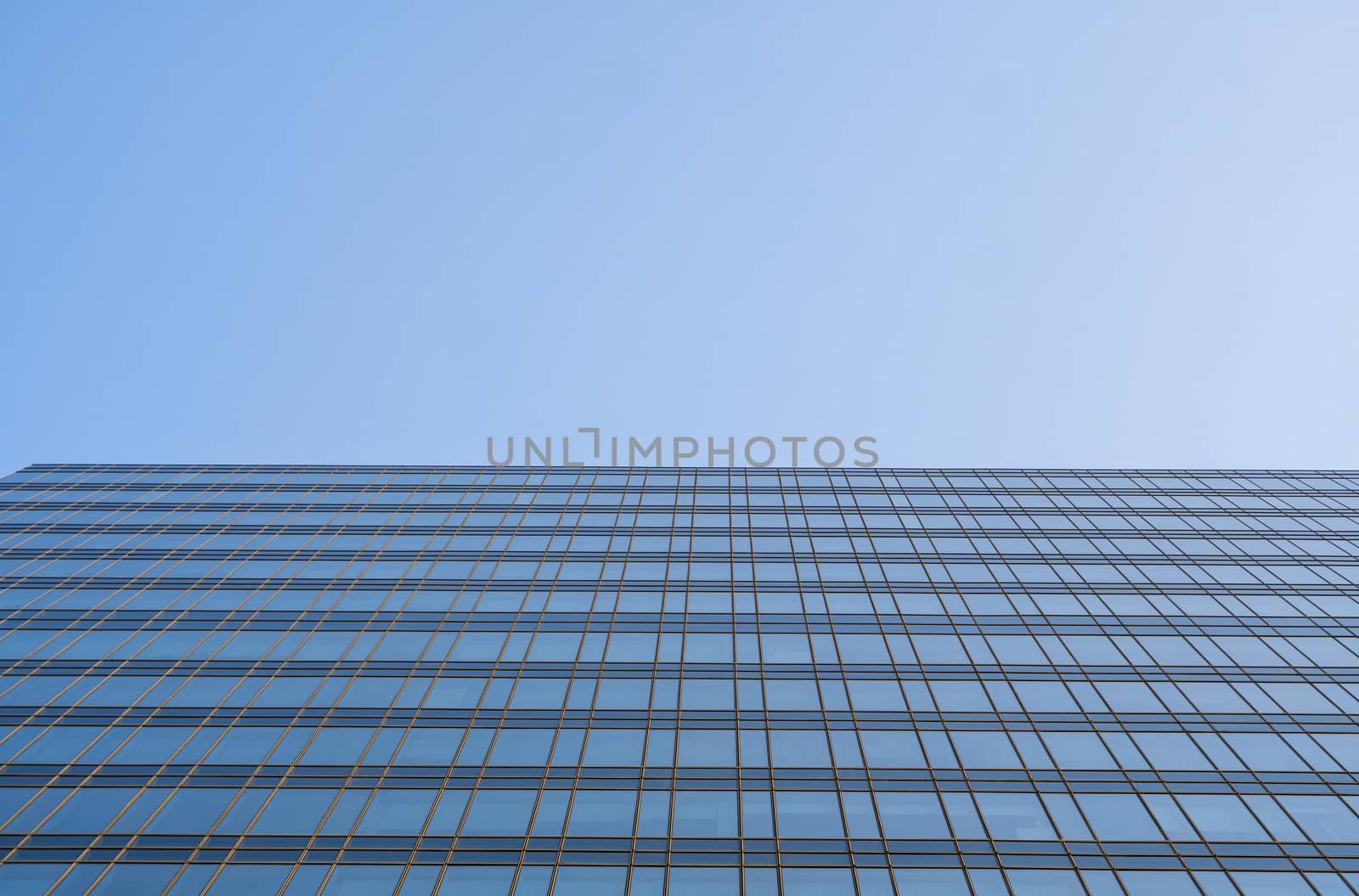 Reflection of the sky in the windows of a building. Perspective and underdite angle view to modern glass building skyscrapers over blue sky. Windows of Bussiness office or corporate building. by vovsht