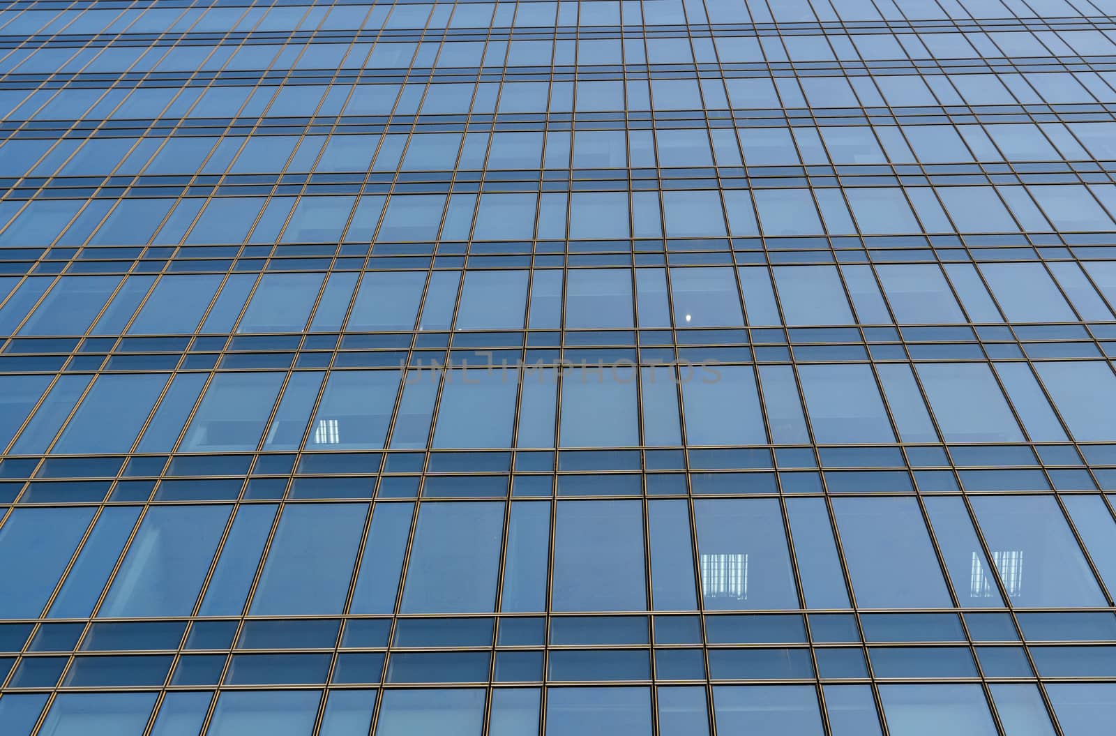 Reflection of the sky in the windows of a building. Perspective and underdite angle view to modern glass building skyscrapers over blue sky. Windows of Bussiness office or corporate building. by vovsht