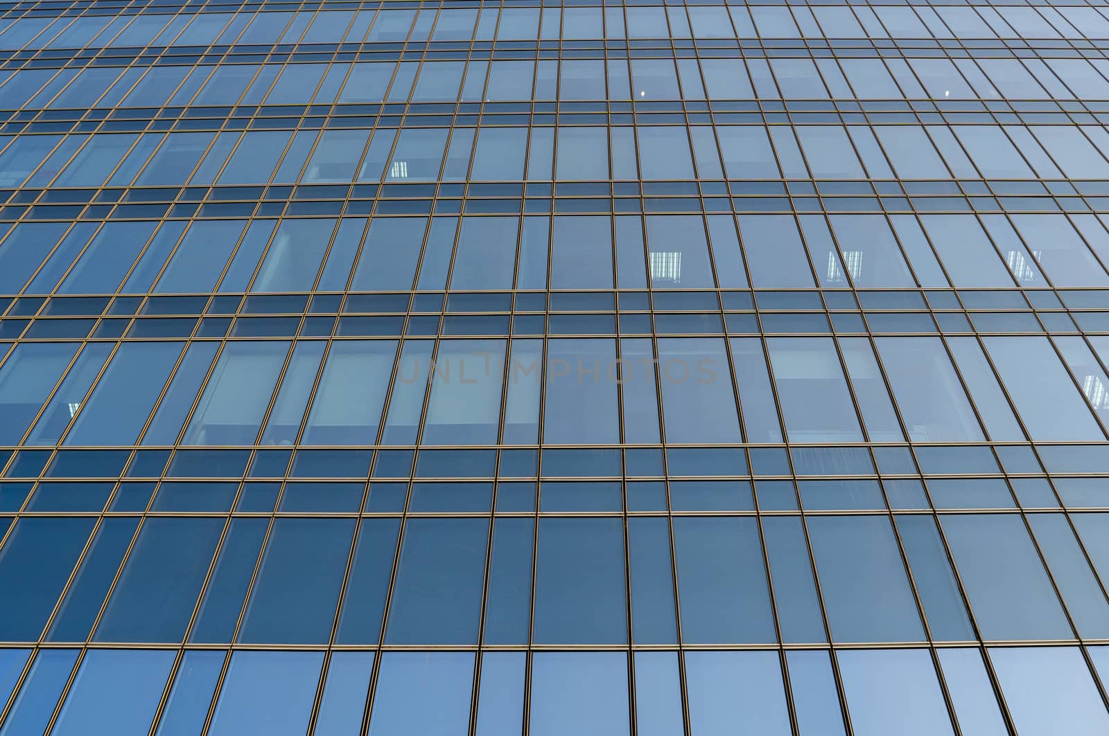 Reflection of the sky in the windows of a building. Perspective and underdite angle view to modern glass building skyscrapers over blue sky. Windows of Bussiness office or corporate building. by vovsht