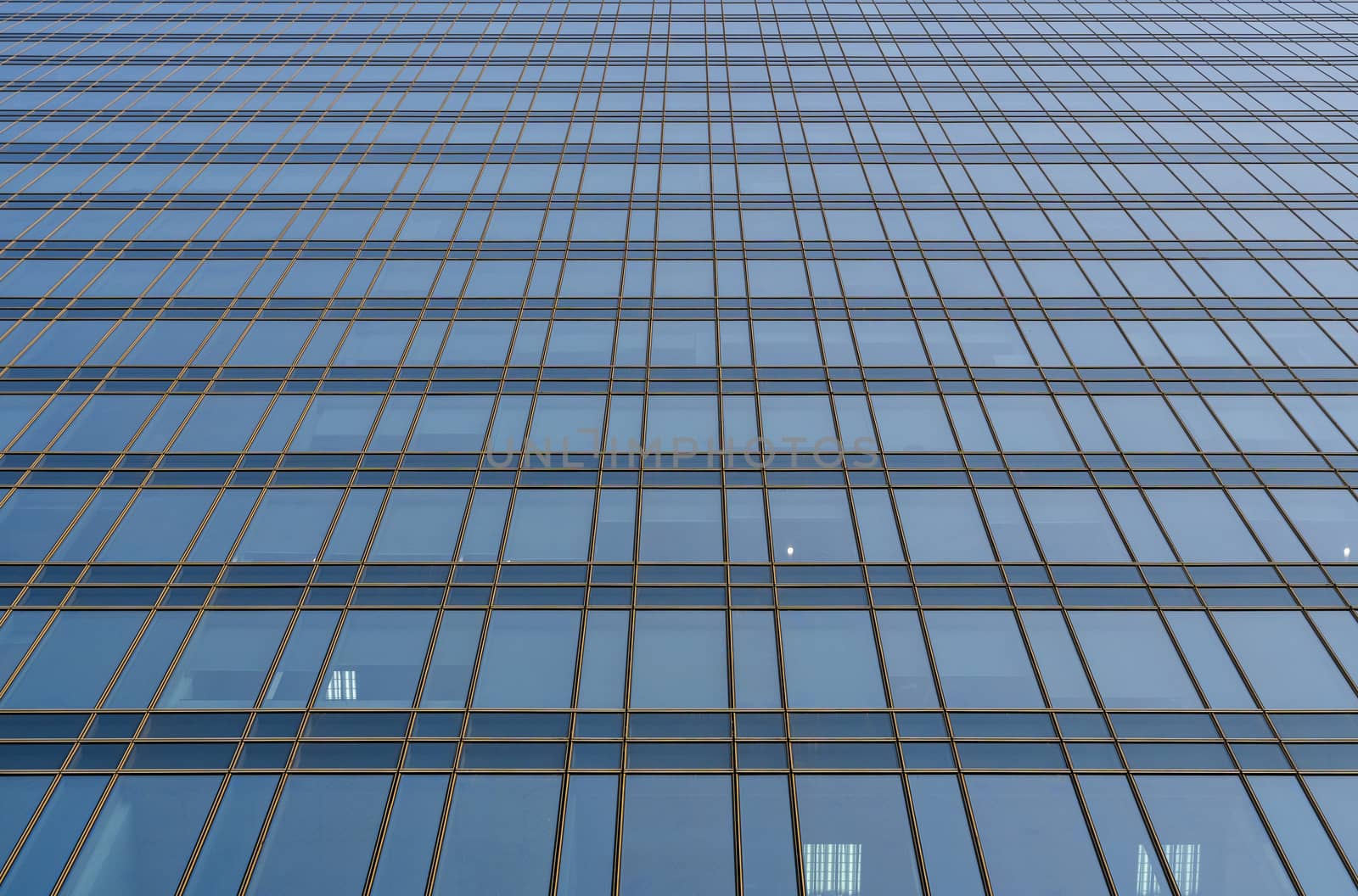 Reflection of the sky in the windows of a building. Perspective and underdite angle view to modern glass building skyscrapers over blue sky. Windows of Bussiness office or corporate building